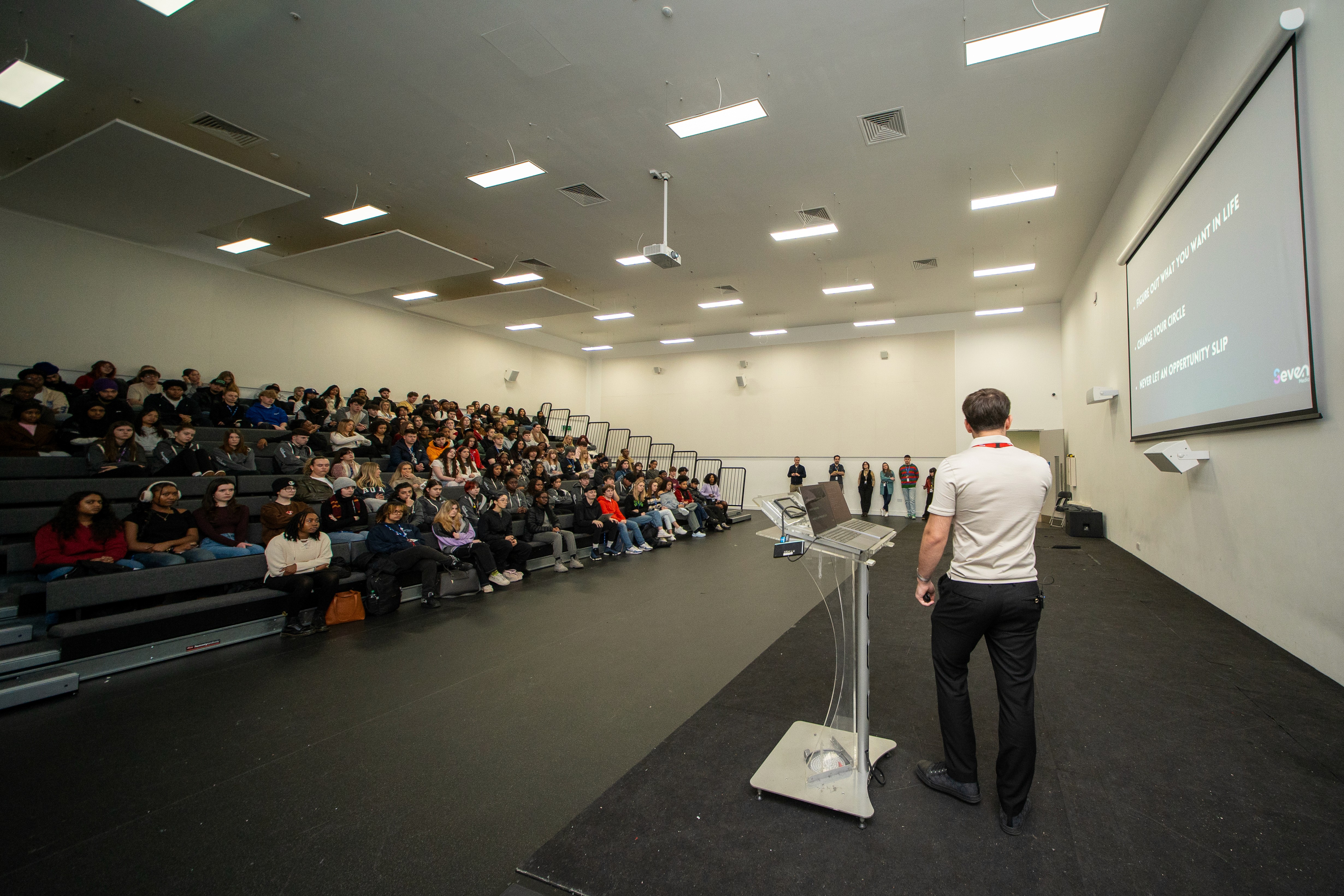 Woman in conical hat rides bicycle down street.