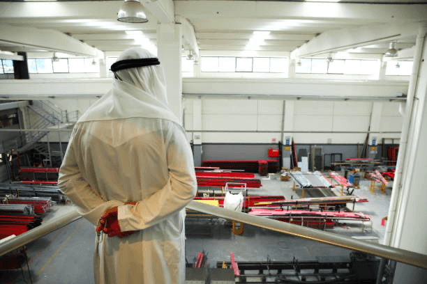 Male scientist wearing safety goggles and a face mask observing a specimen through a microscope in a laboratory setting.