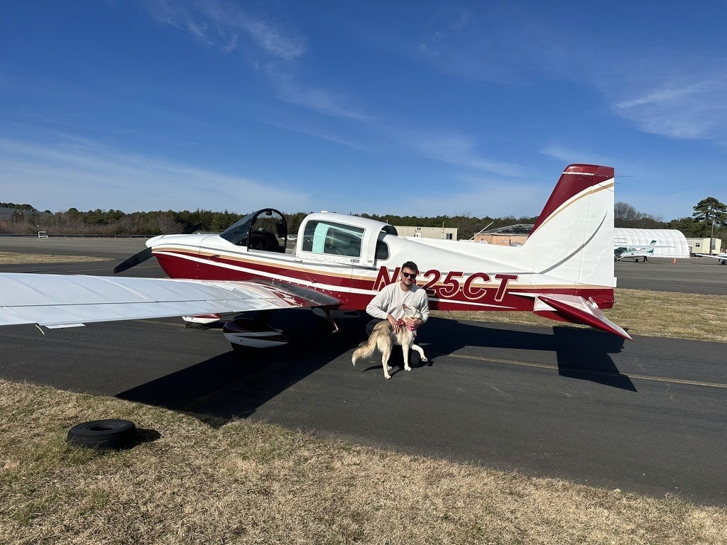 Dillon Ponzo with a rescue dog beside a small airplane.
