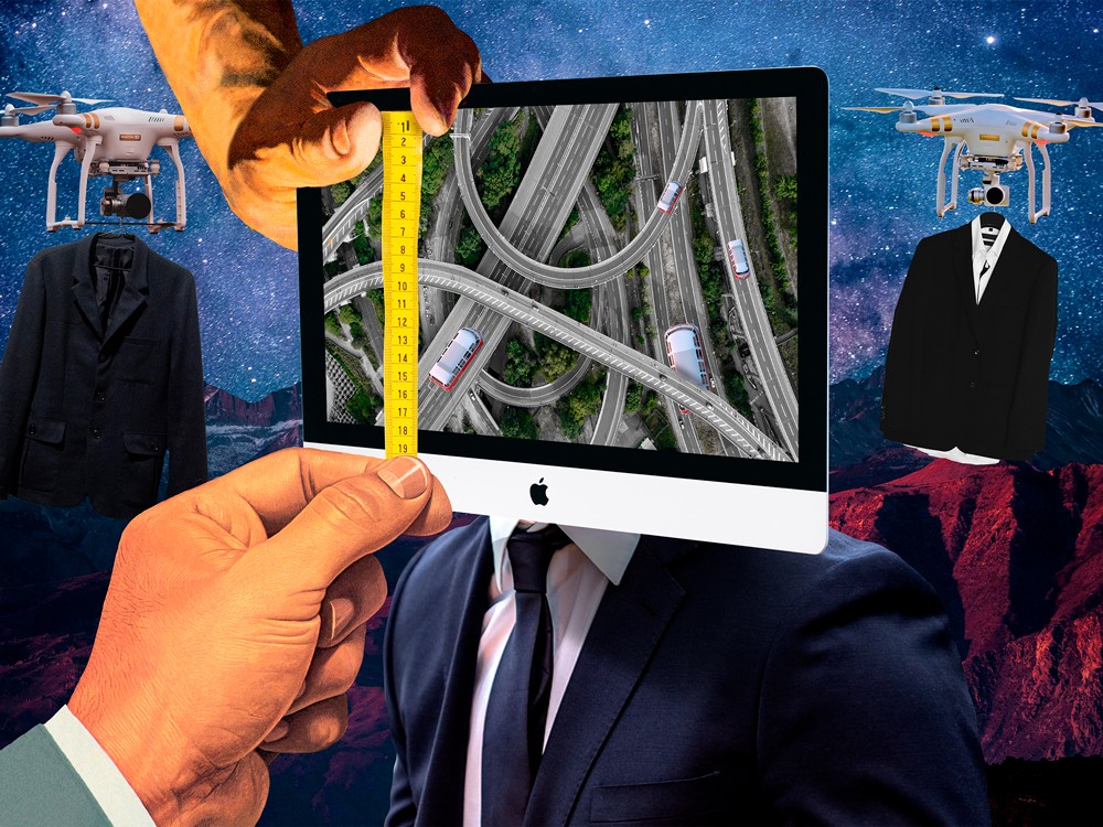 Hombre en traje con monitor mostrando carreteras aéreas, drones y paisaje de fondo.