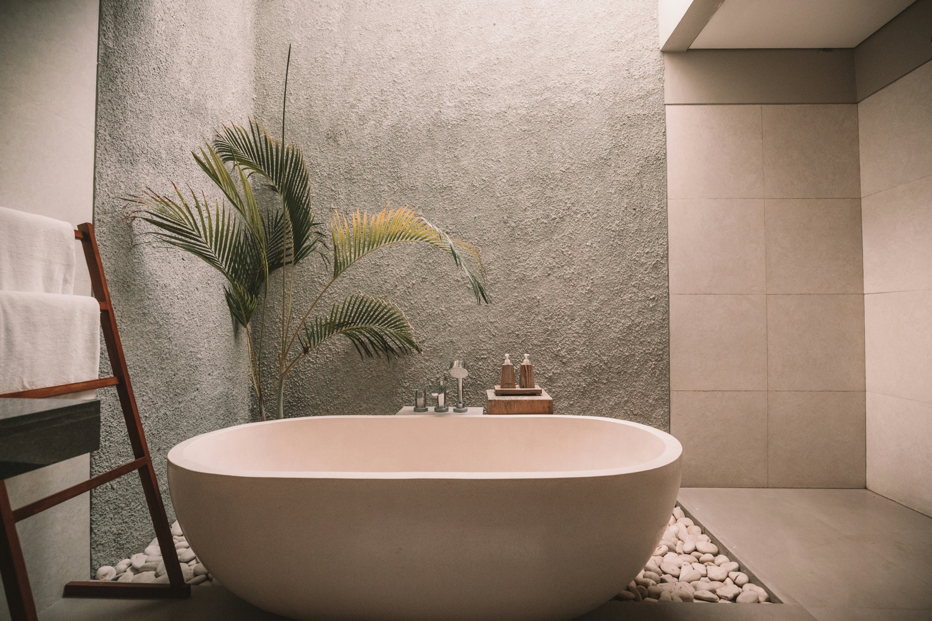 A freestanding bathtub in a calm stone bathroom.