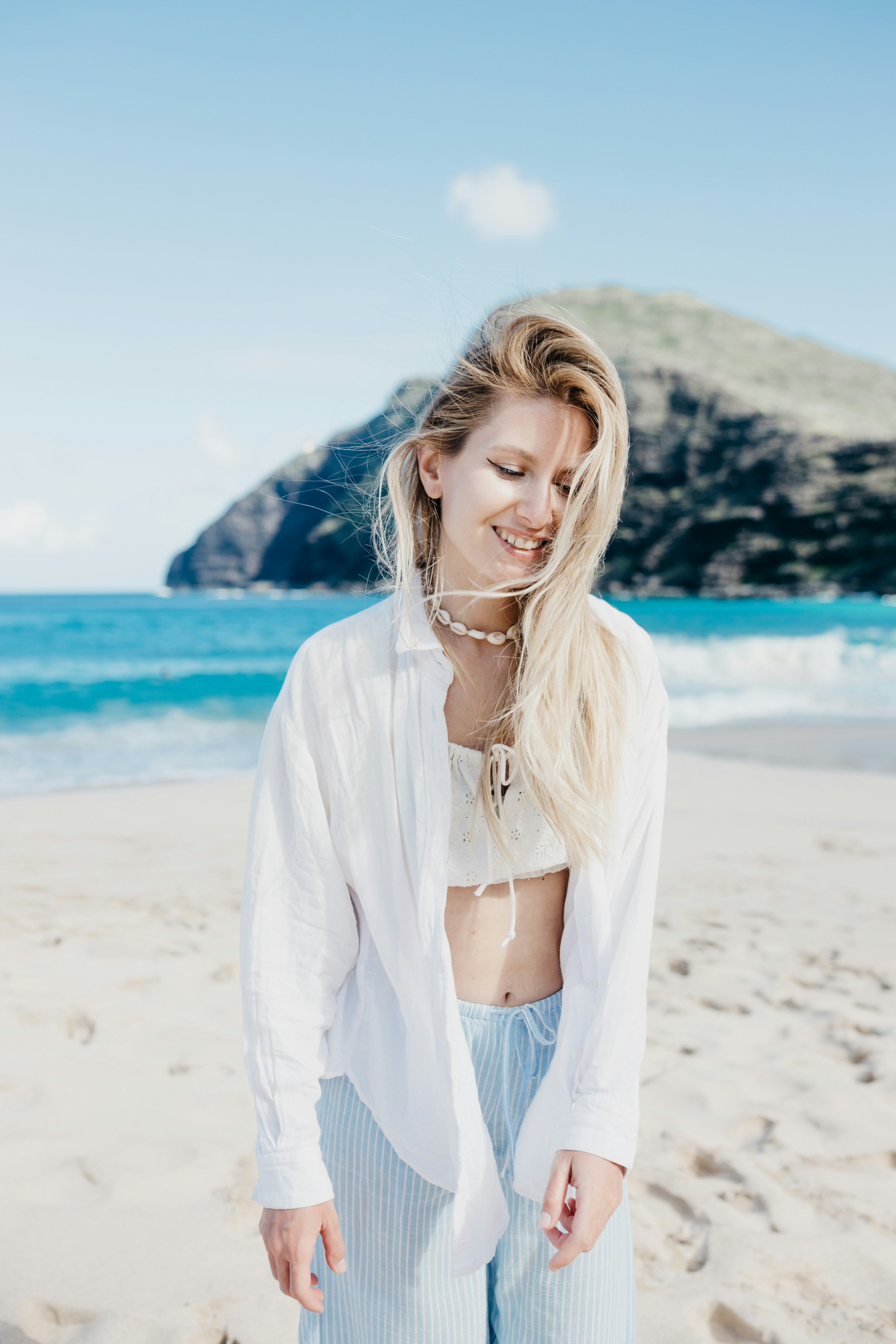 Young woman smiling on a sunny beach with ocean background