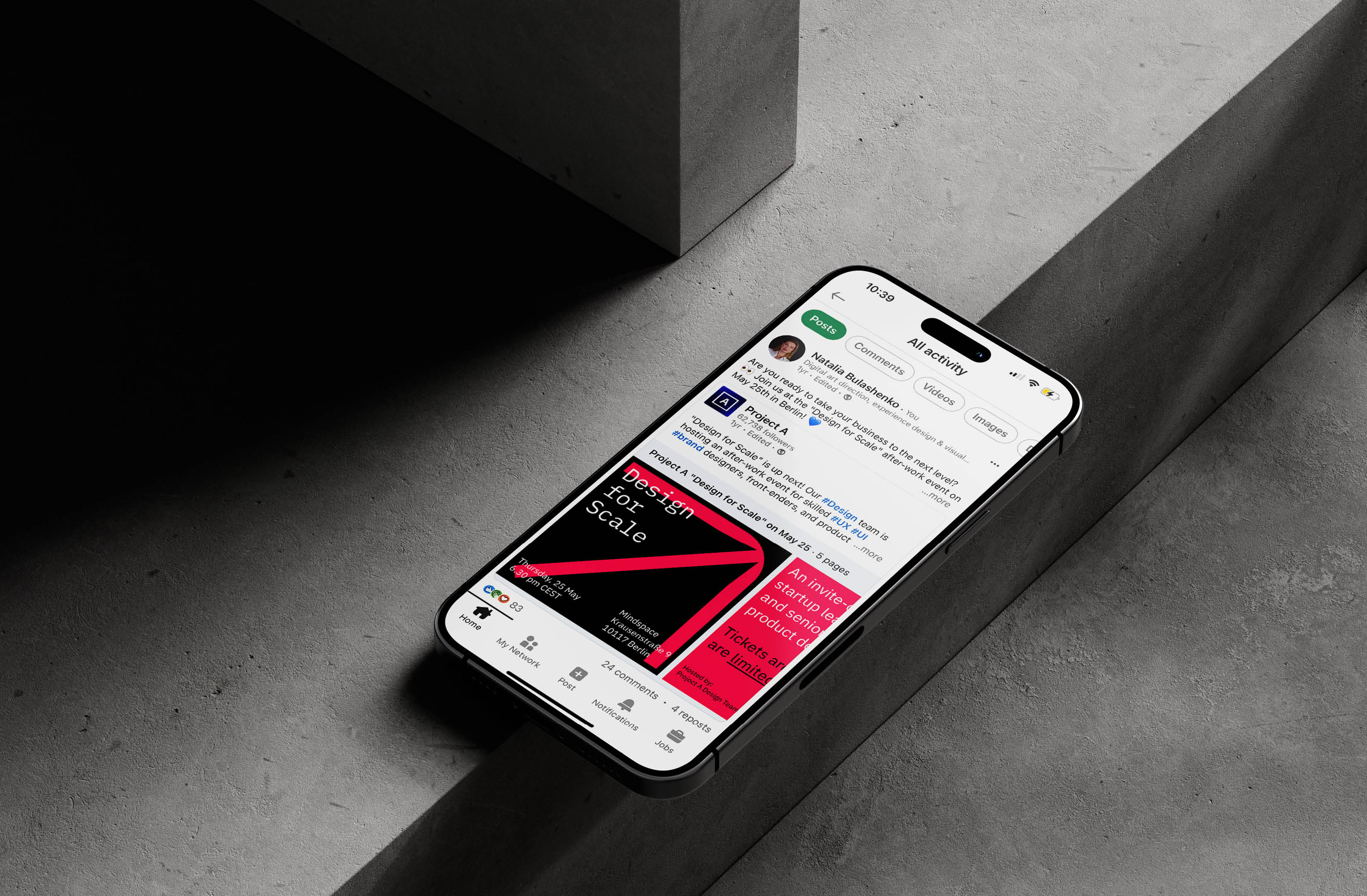 Close-up of a smartphone displaying social media content about a design event, showcasing posts and interactive features.