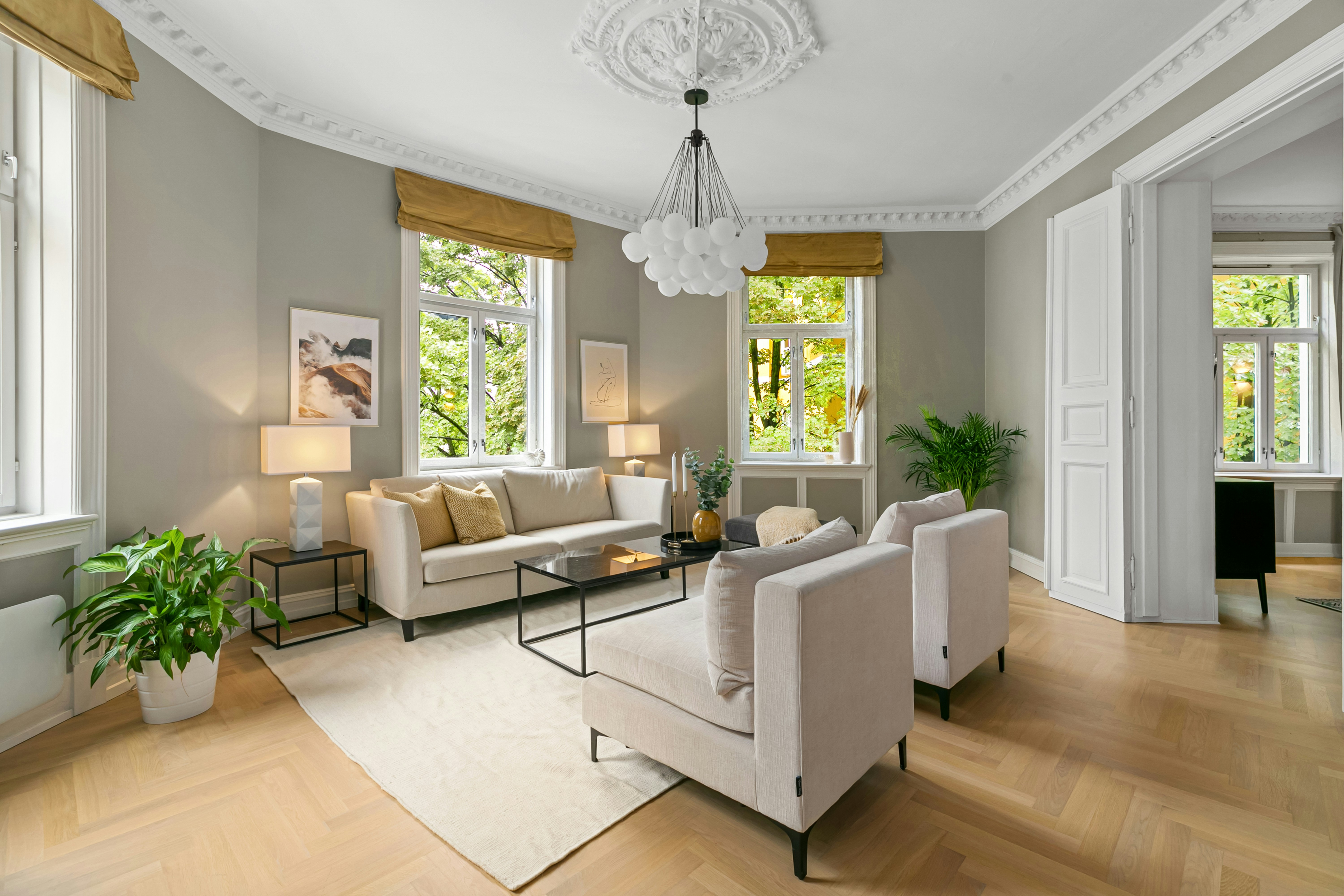 Elegant Scandinavian living room with ornate plasterwork, herringbone floors, and gold Roman blinds