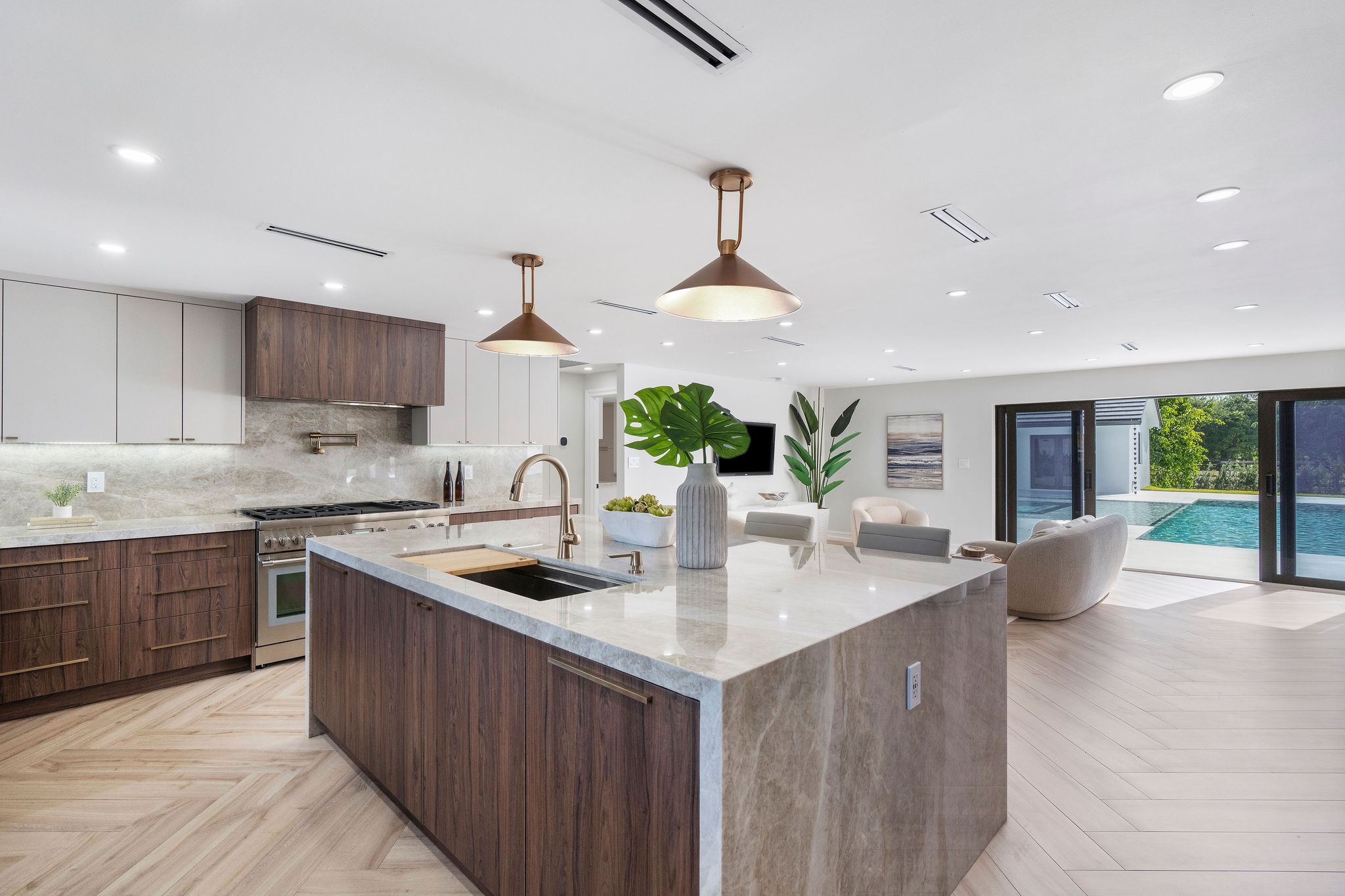 Modern kitchen island with marble countertop, pendant lights, and view of a pool.