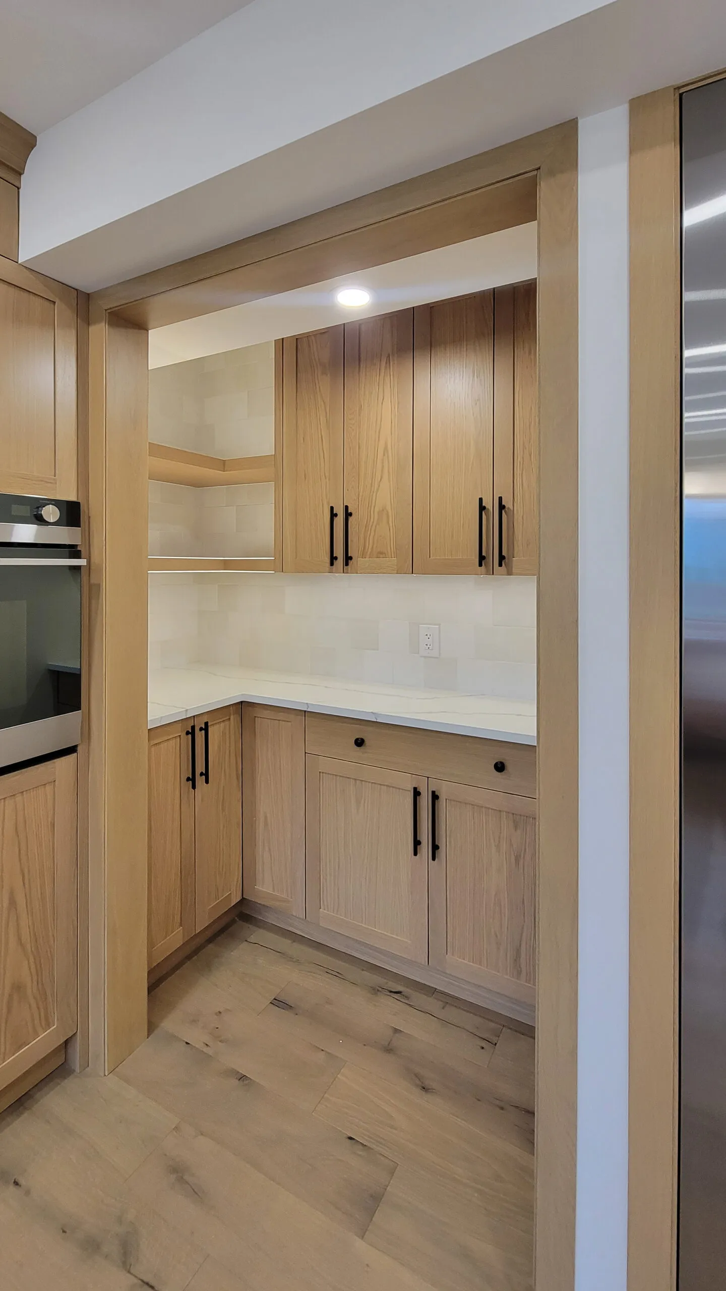 Image of warm wood bakers nook with light artisan textural tiles and light countertop.