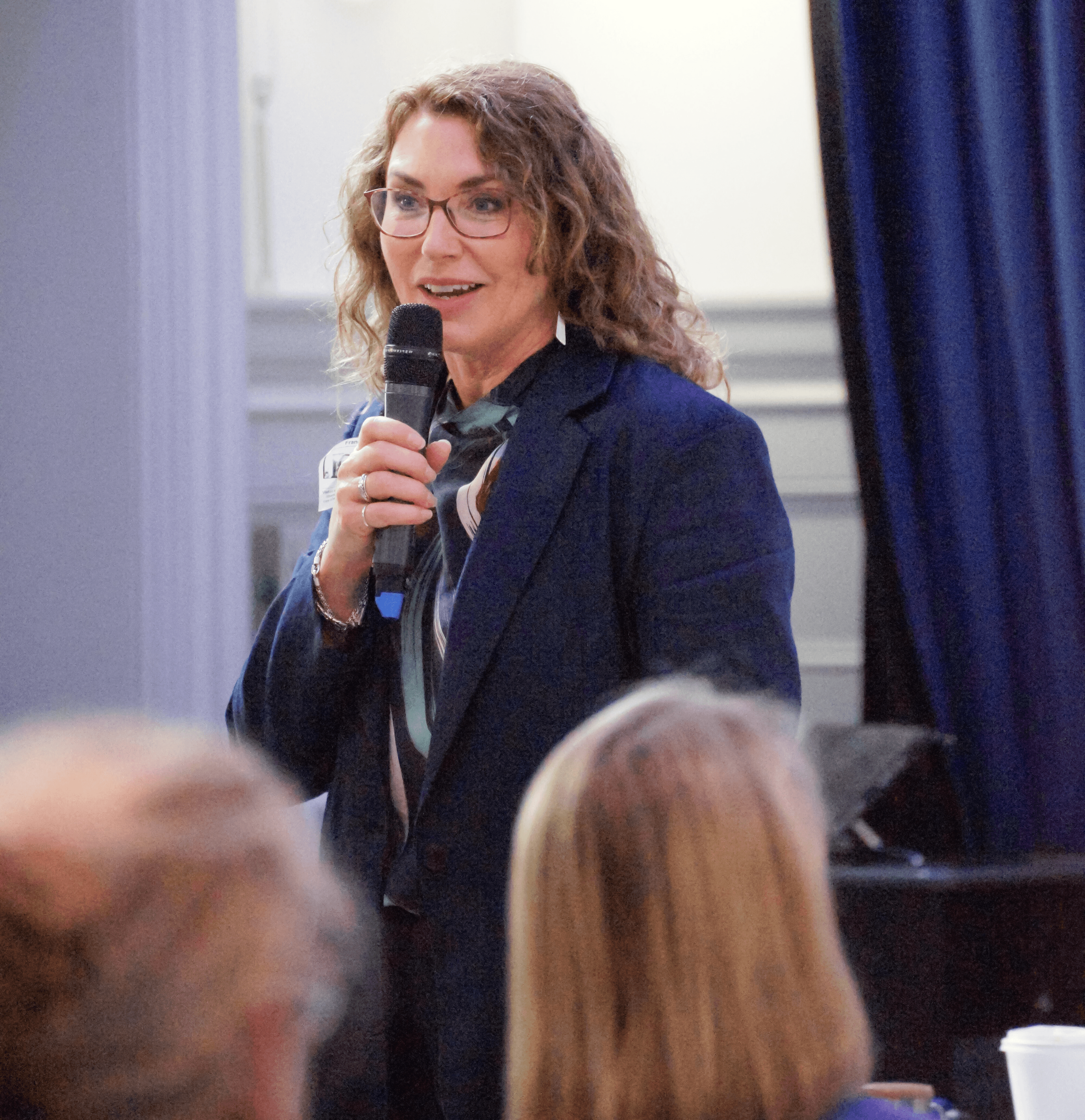 Person speaking at an outdoor event with people and a microphone.