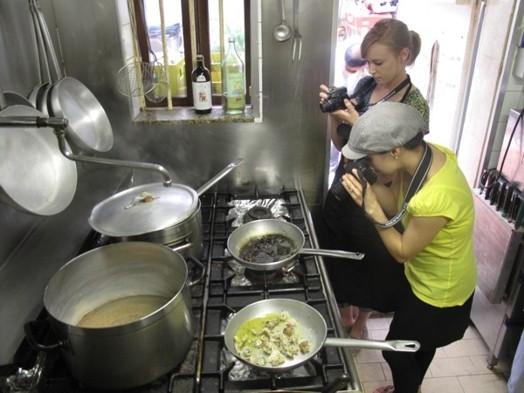 A photo of two girls taking photos in a kitchen.