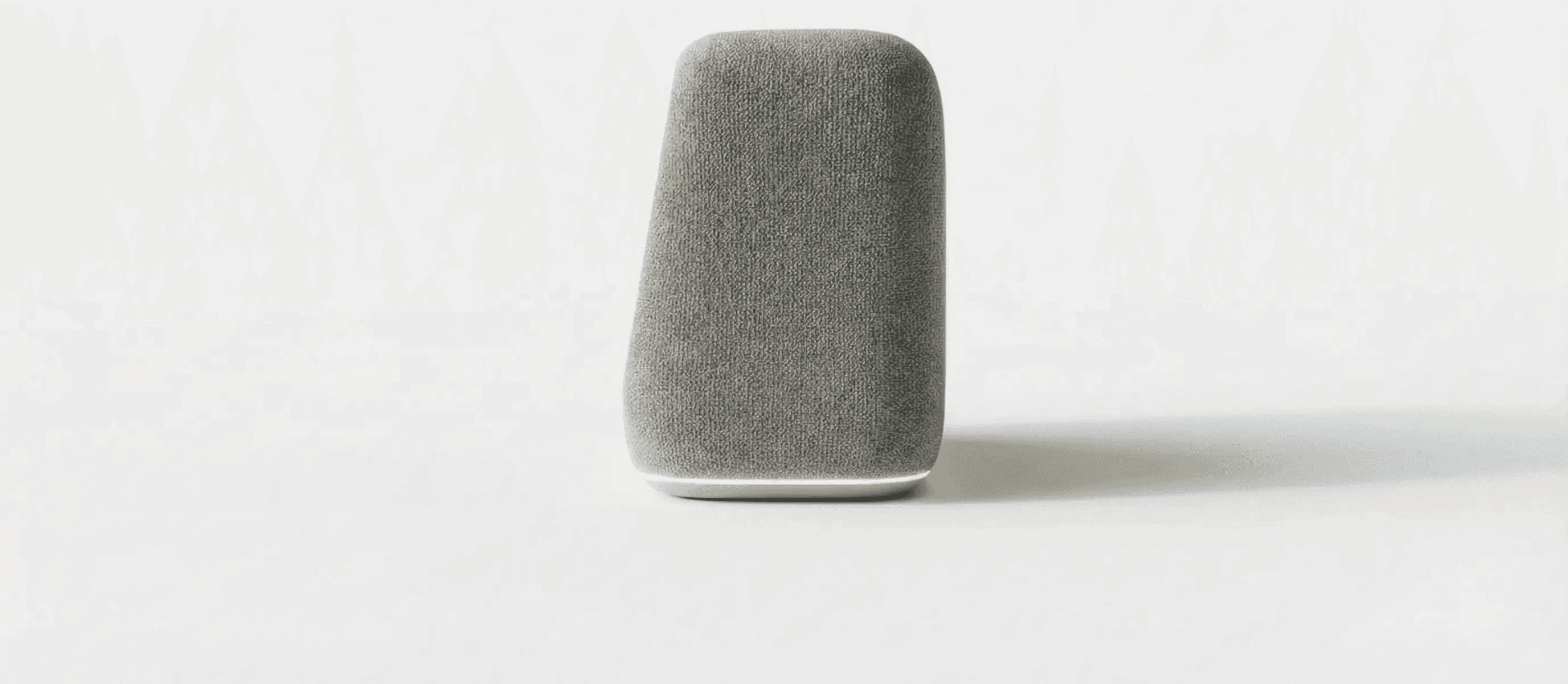 A minimalist gray stone sitting on a white surface, casting a soft shadow beside it.
