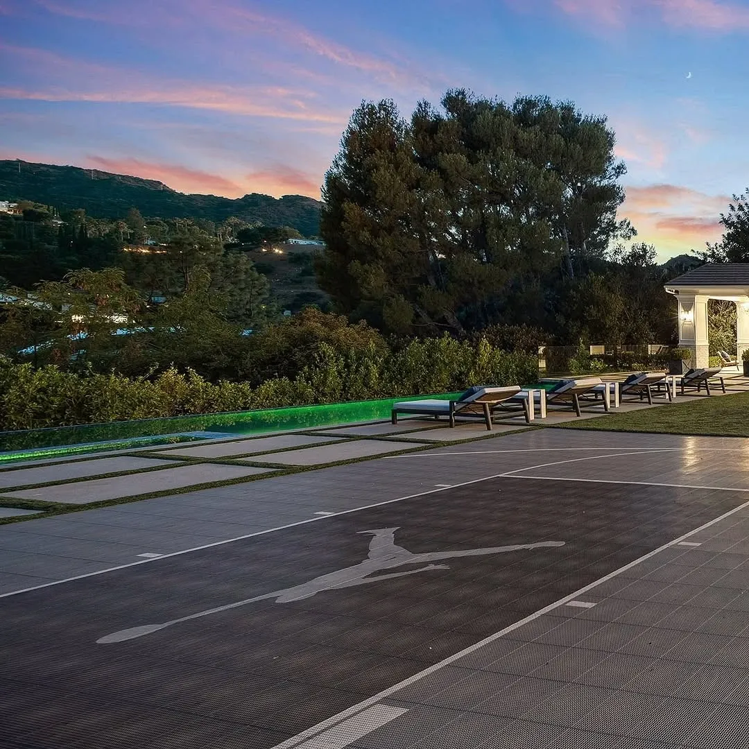 Scenic outdoor area with a paved driveway, green lawn, and trees at dusk.
