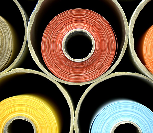 A man and woman sit on beige chairs in a modern room with a red paneled wall. A red pendant light hangs above a wooden coffee table between them.