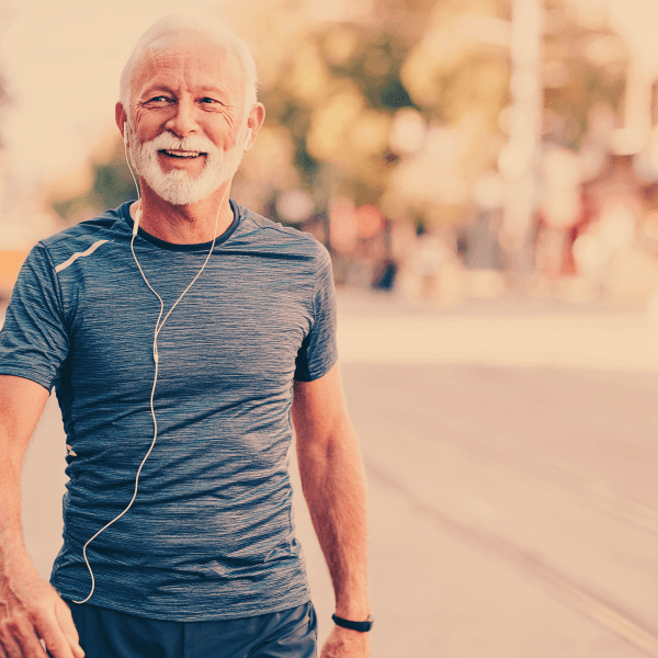 Healthy retiree male muscular in blue fitted t-shirt walking towards camera smiling