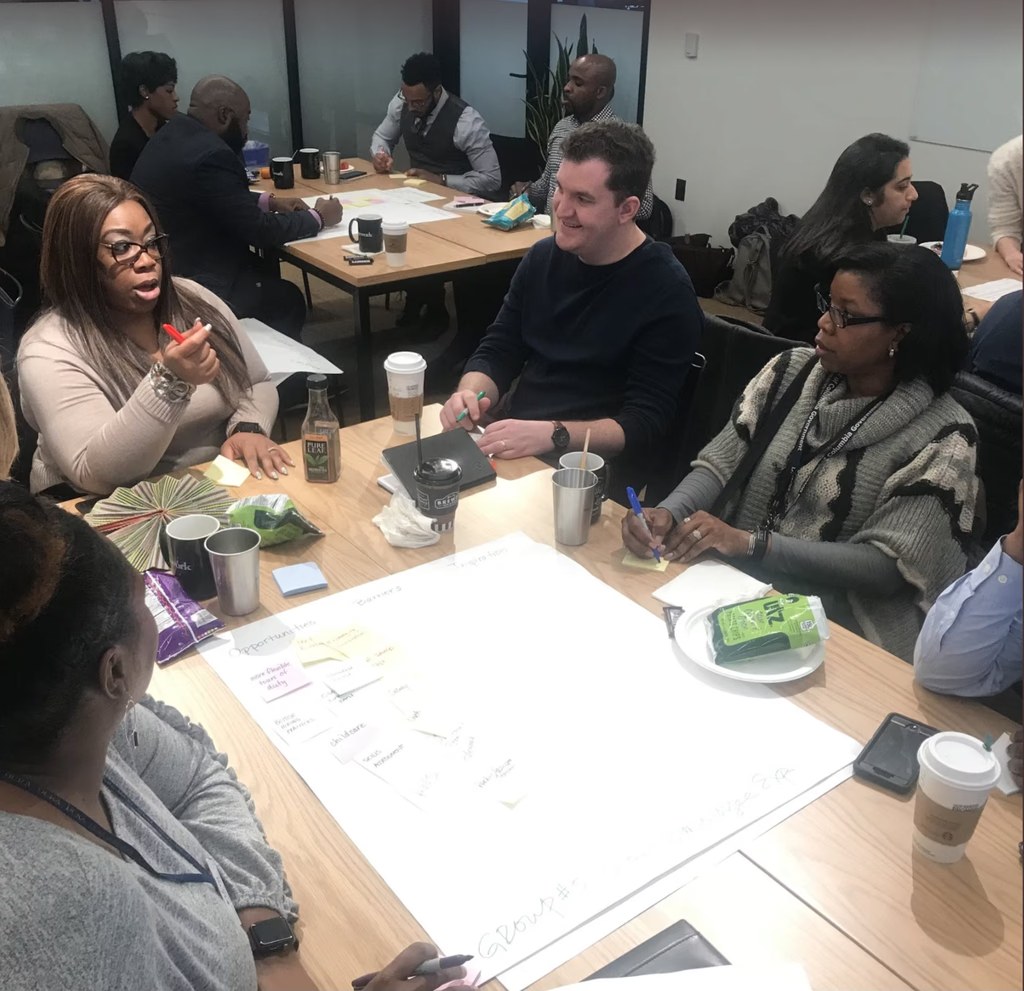 A team working session around a table, sorting sticky notes on a shared board