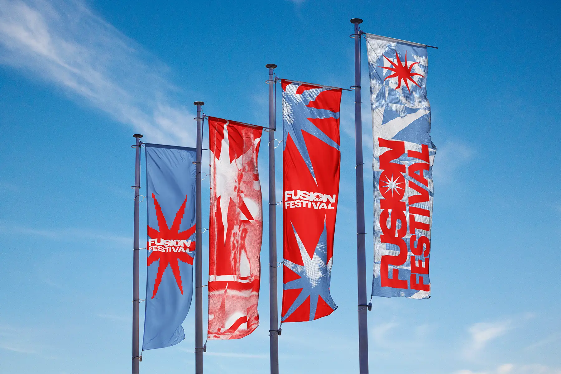 Four tall Fusion Festival banner flags in blue and red against a blue sky