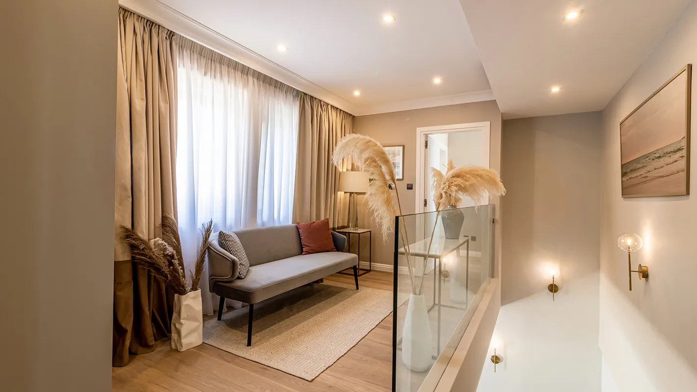 White Cedar House Mediterranean upstairs landing with lounge nook, glass balustrade, and soft neutral styling