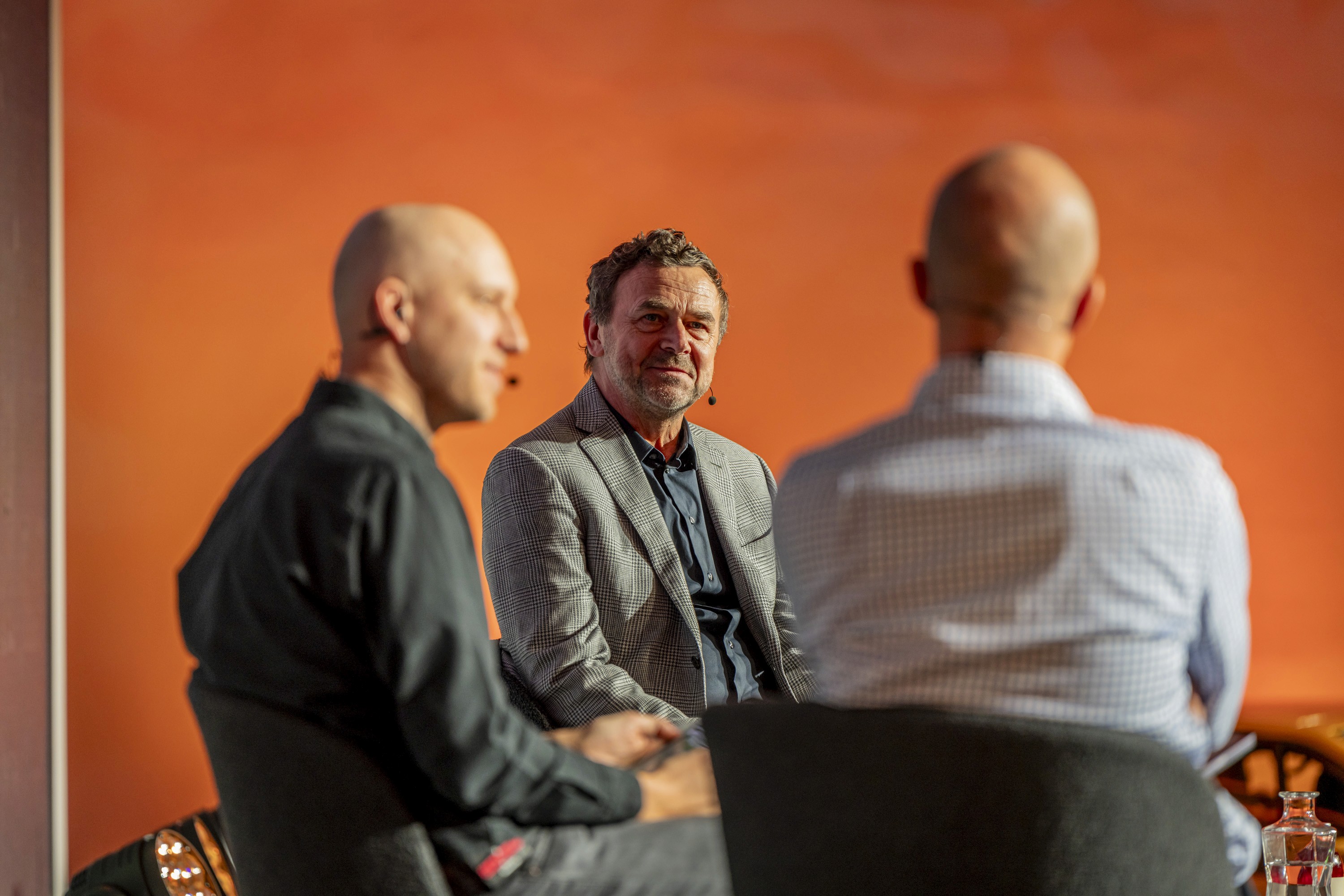 On-stage interview with a guest speaker being interviewed by two hosts during a business conference.