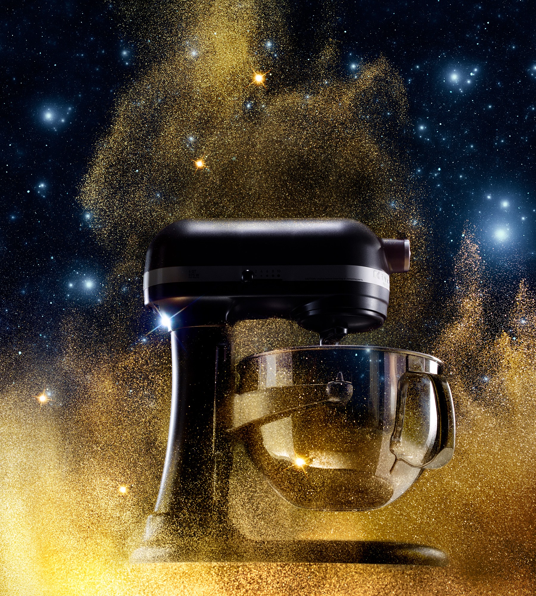 A cake mixer within a cloud of gold stardust against an outer space background