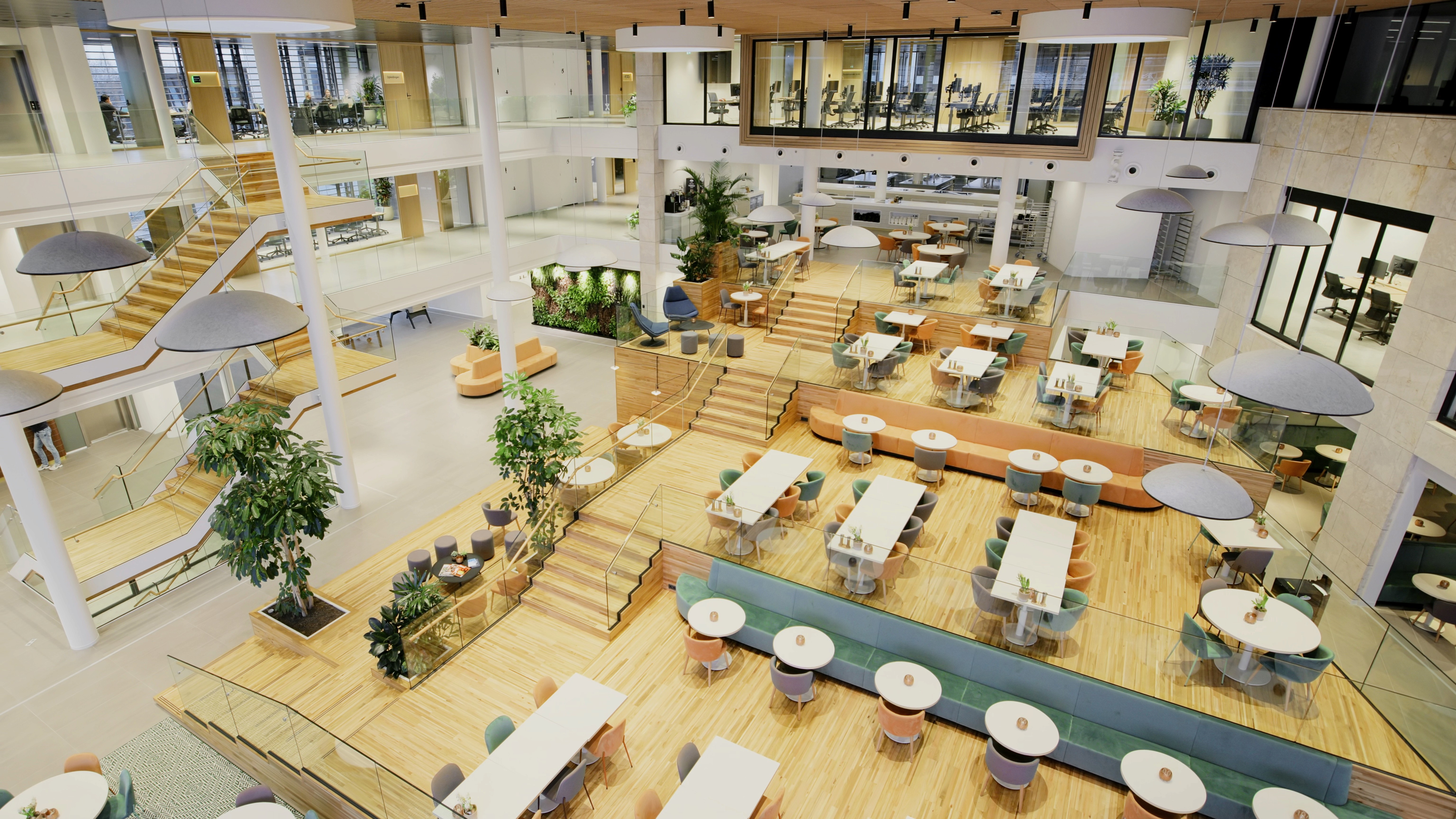 Overzicht: Gerard van DSN Workspace Solutions tijdens walkaround door AFAS DotNL – bovenaanzicht van het open kantooratrium met werkplekken, lounge-eilanden en trappen