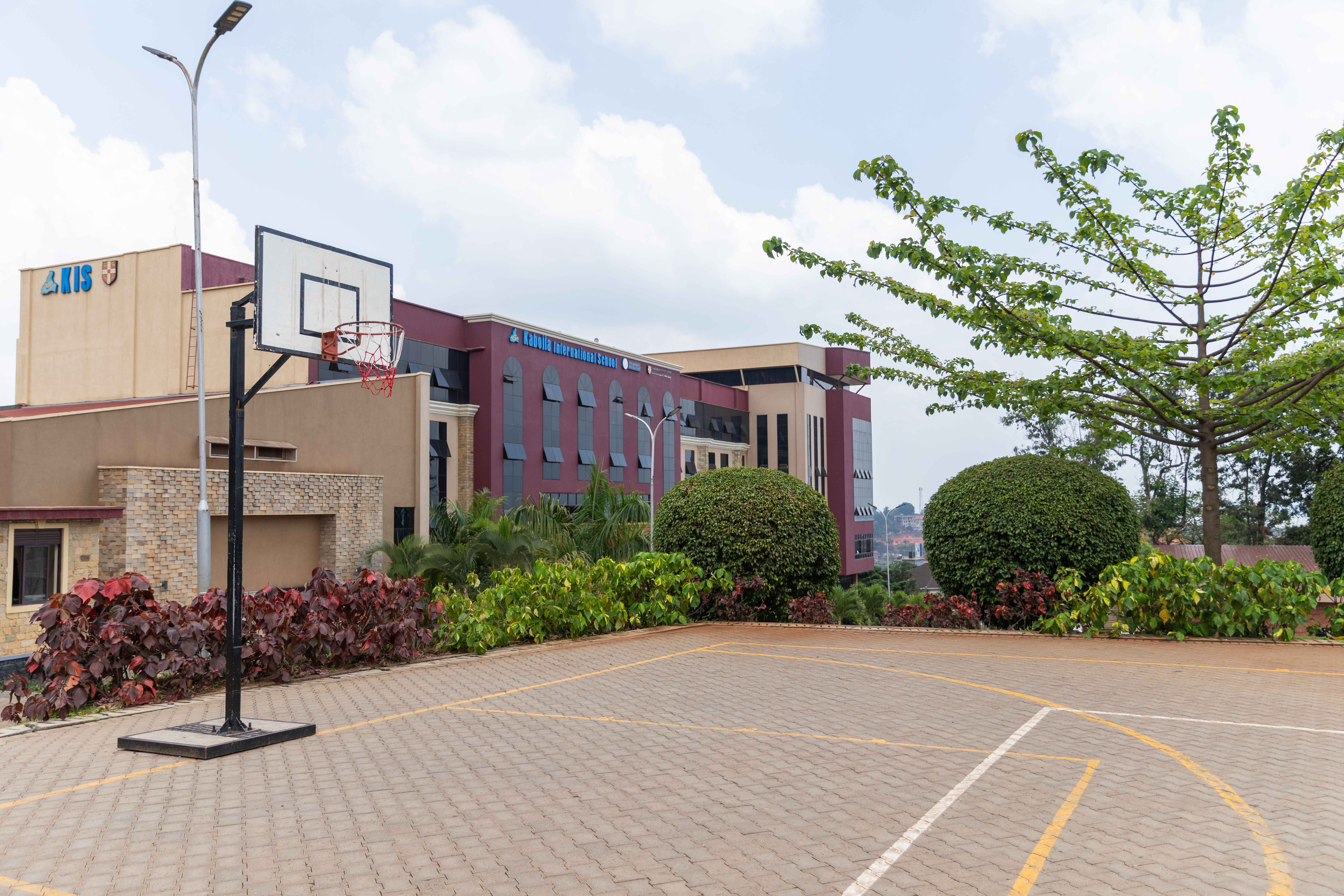 A student wearing a red uniform sits while holding a book in his hands