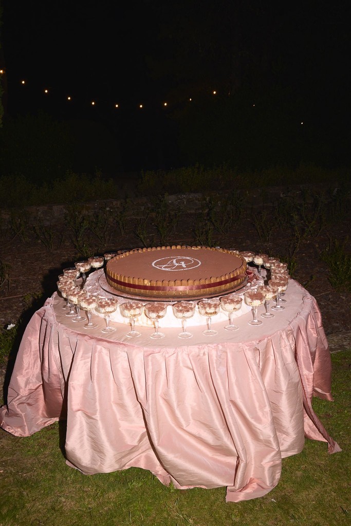 Round tiramisu cake displayed on a silk-draped table during the evening reception