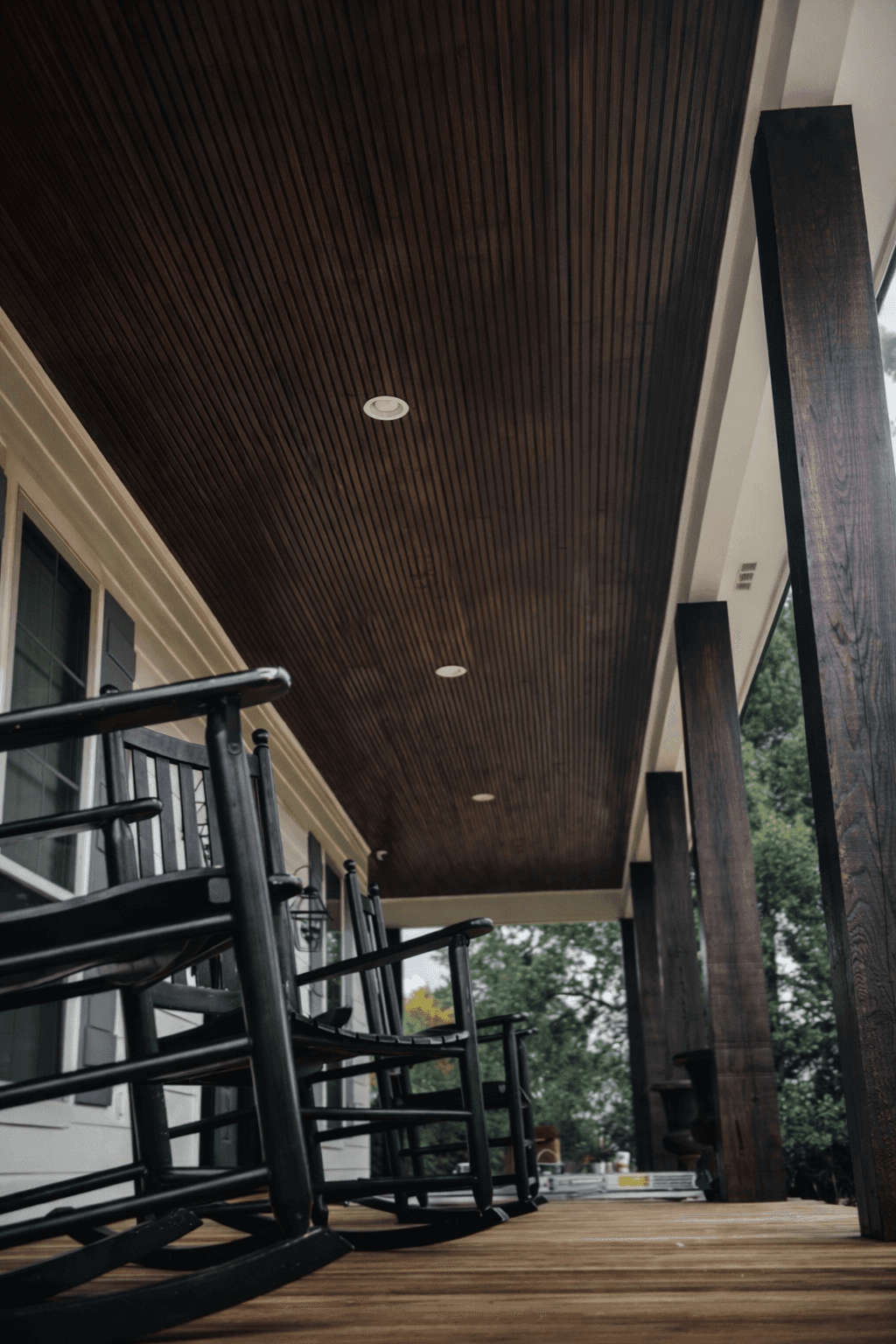 Modern kitchen with a wooden dining table, white chairs, and a hanging light fixture above.