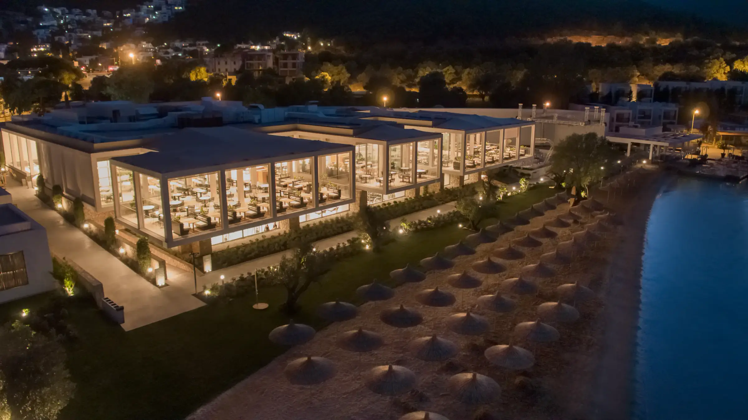 Shoreline restaurant and beach parasols lit at night