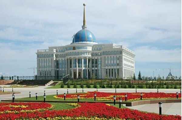 The Akorda Presidential Palace in Astana Kazakhstan. The building has a blue dome on top. Red flowers are in front of the palace.