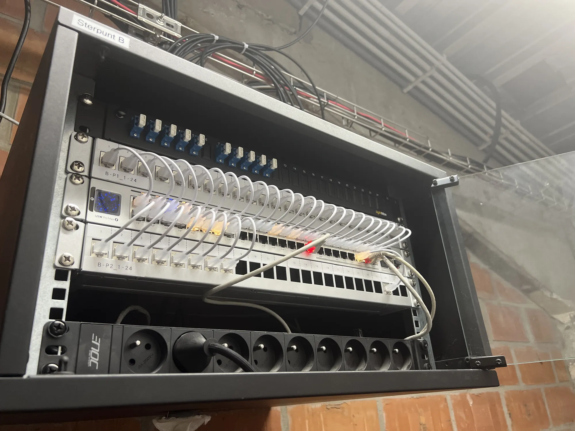 Open wandkast met patchpanelen, switch en stroomverdeling