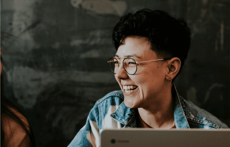 A smiling person with glasses photographed in a casual setting with a dark background