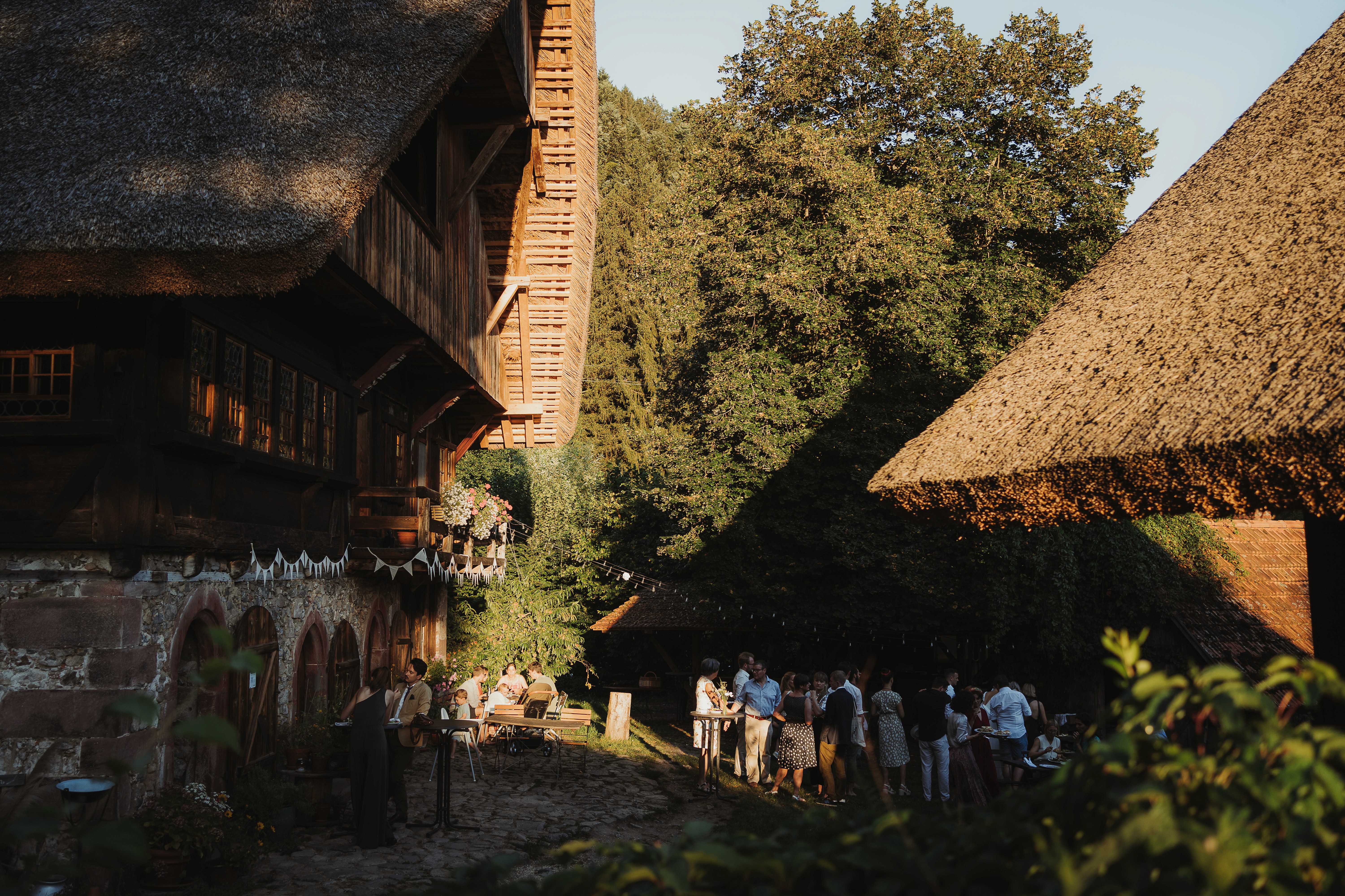 Hochzeitsgäste vor dem Hauptgebäude in der Abendsonne.
