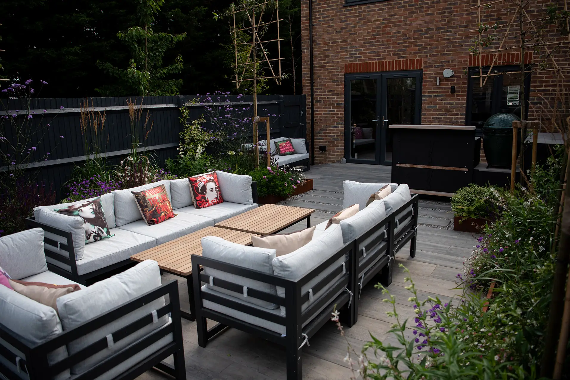 A cozy outdoor seating area featuring a sectional sofa, coffee table, and greenery in a well-lit space.