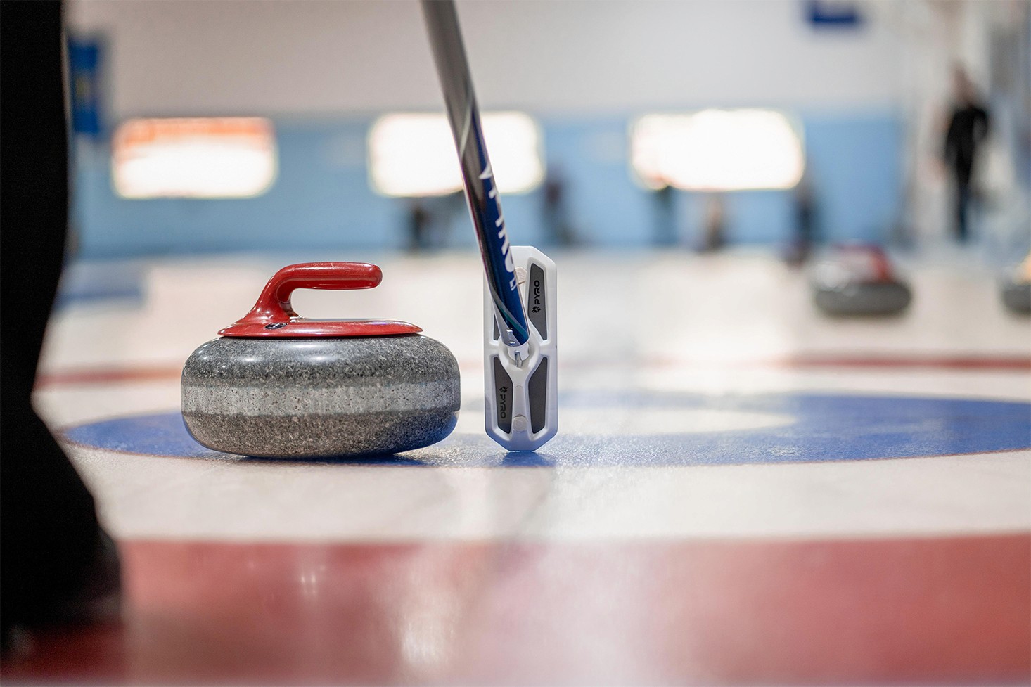 A curler puts his broom beside a curling rock to lineup a shot