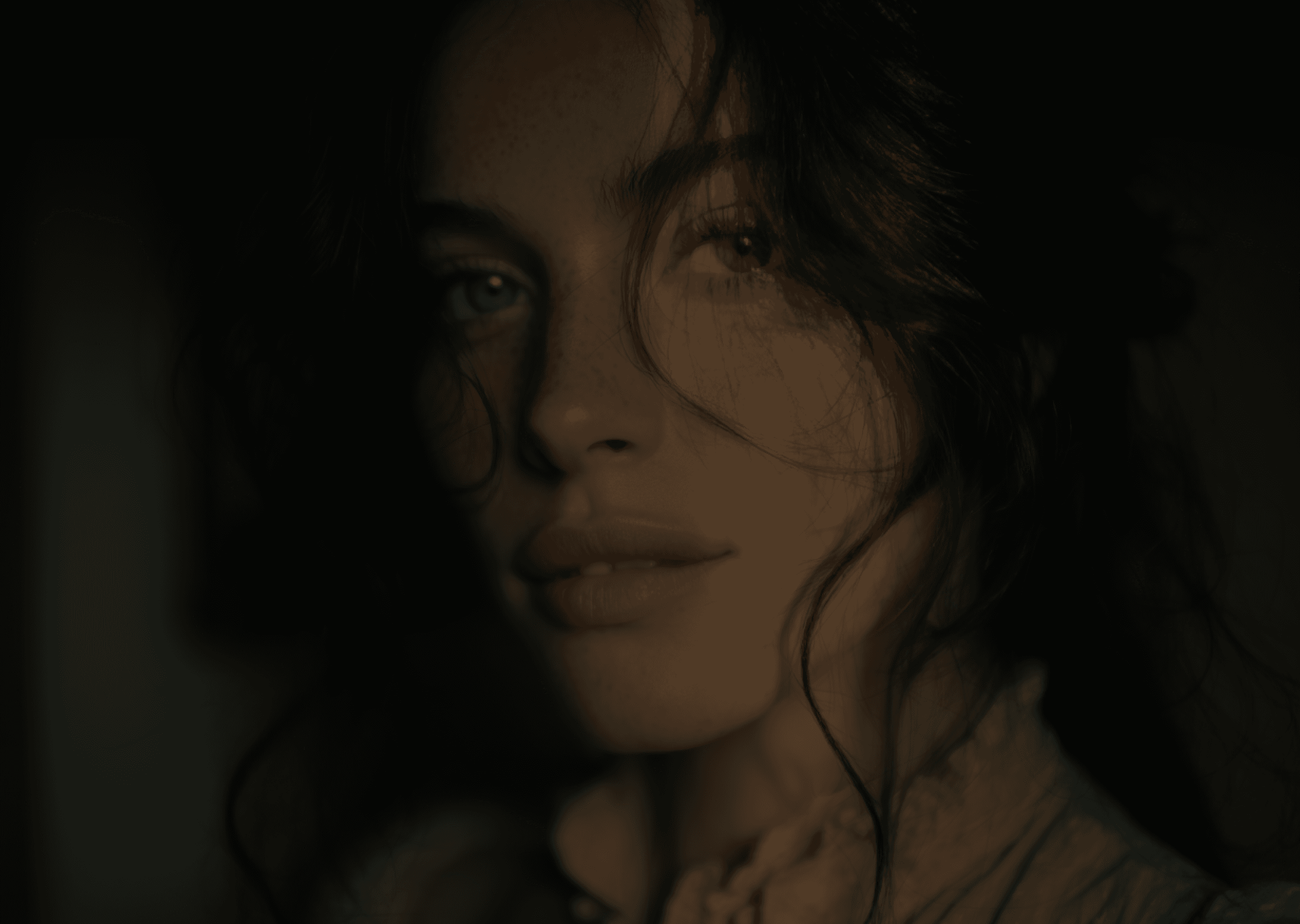 Close-up of a woman with dark hair and light eyes, her face partially in shadow.