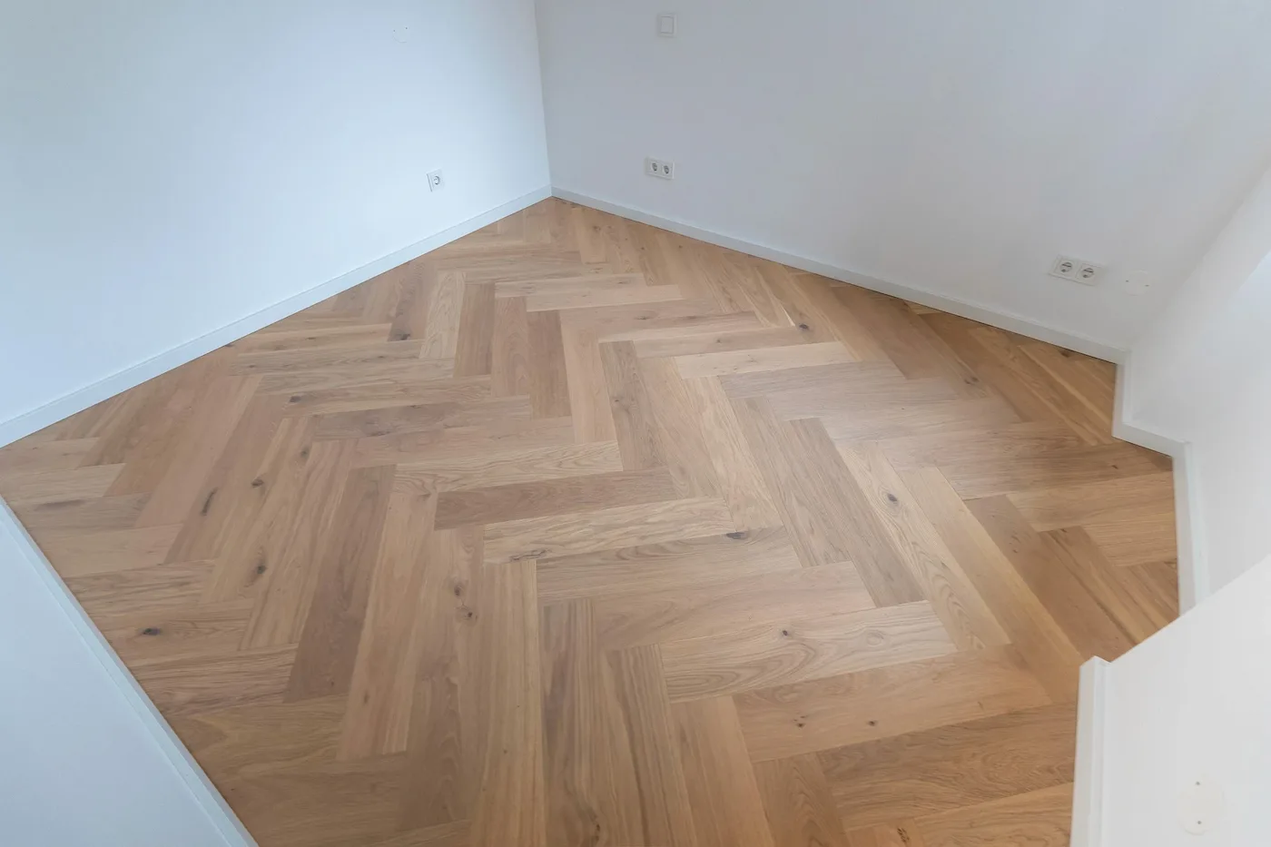 Kleiner Raum mit hochwertigem Fischgrät-Parkettboden in hellem Holzton.