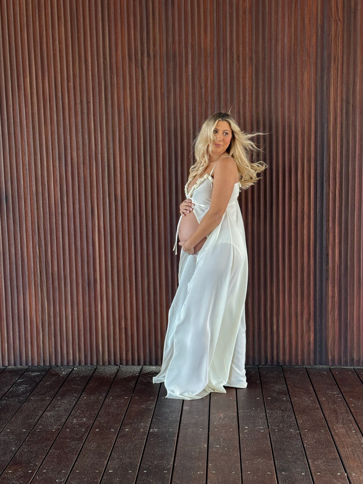 Ivory satin floor-length gown with delicate straps, soft V neckline, relaxed empire silhouette, and fluid draped skirt