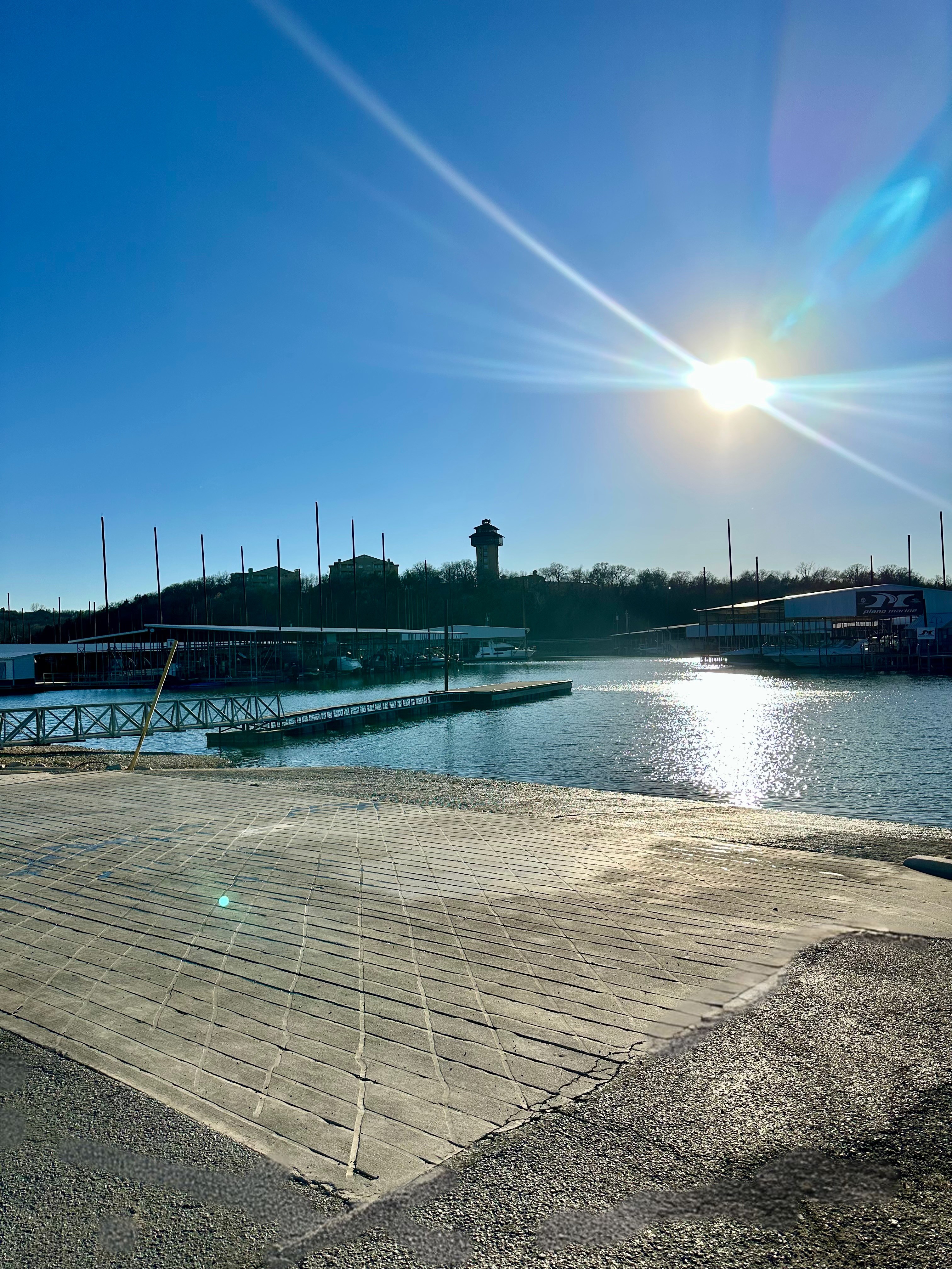 Boat lift system with two blue pontoons and metal framework, positioned between two docks, in a marina setting.
