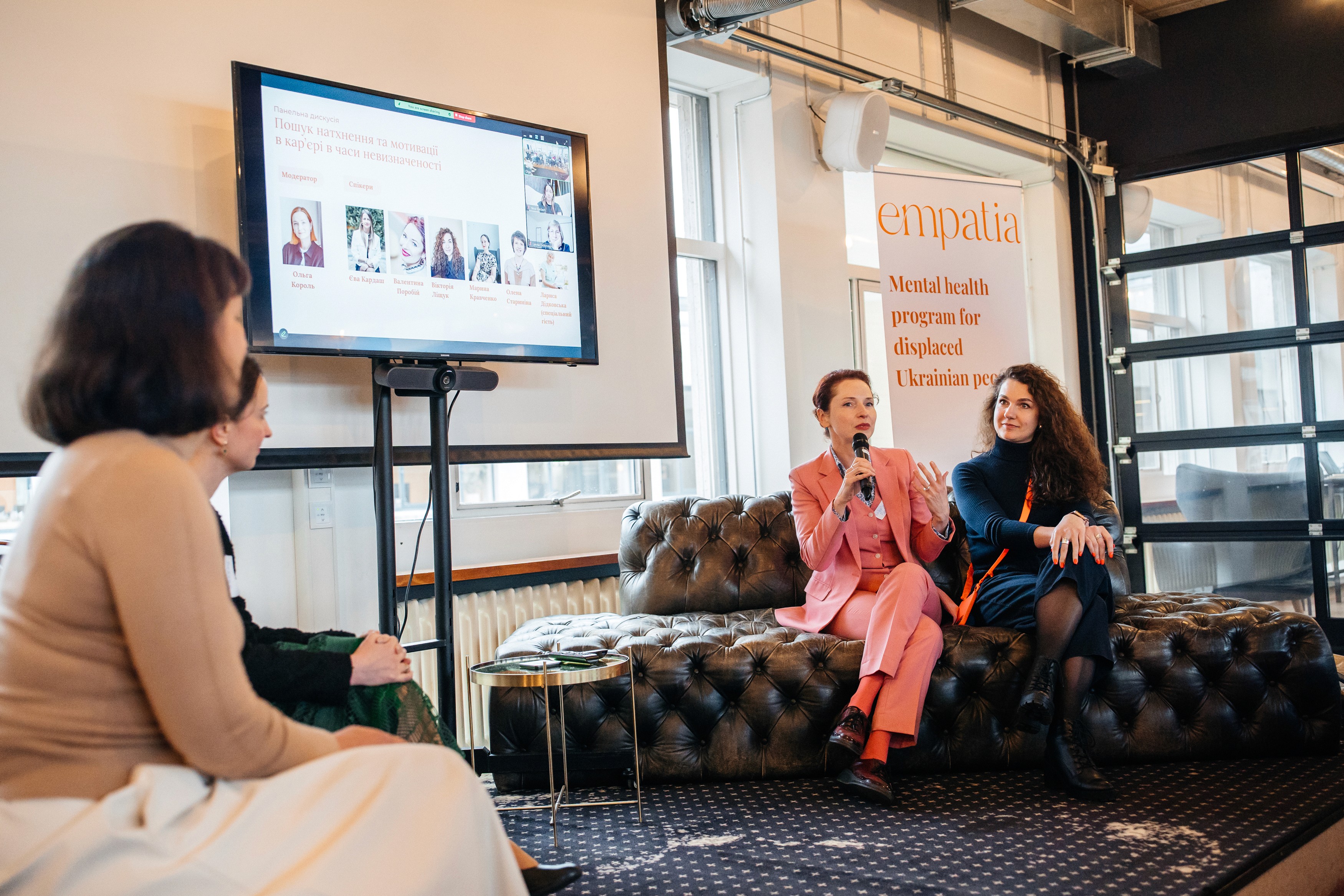 Panel of Ukrainian mental health professionals speaking during the Empatia Program event in the Netherlands, with presentation slides and banner in the background.