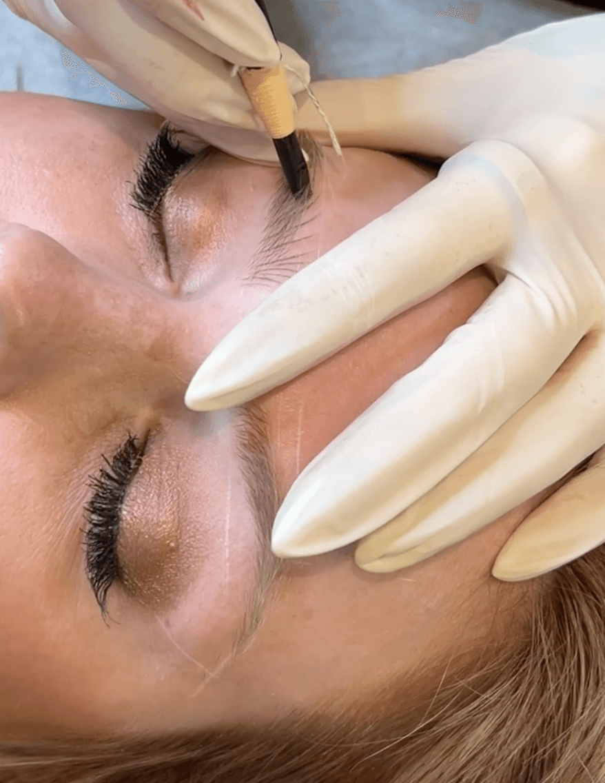 Woman sitting in sunlight with eyes closed, wearing relaxed neutral clothing in a peaceful setting.