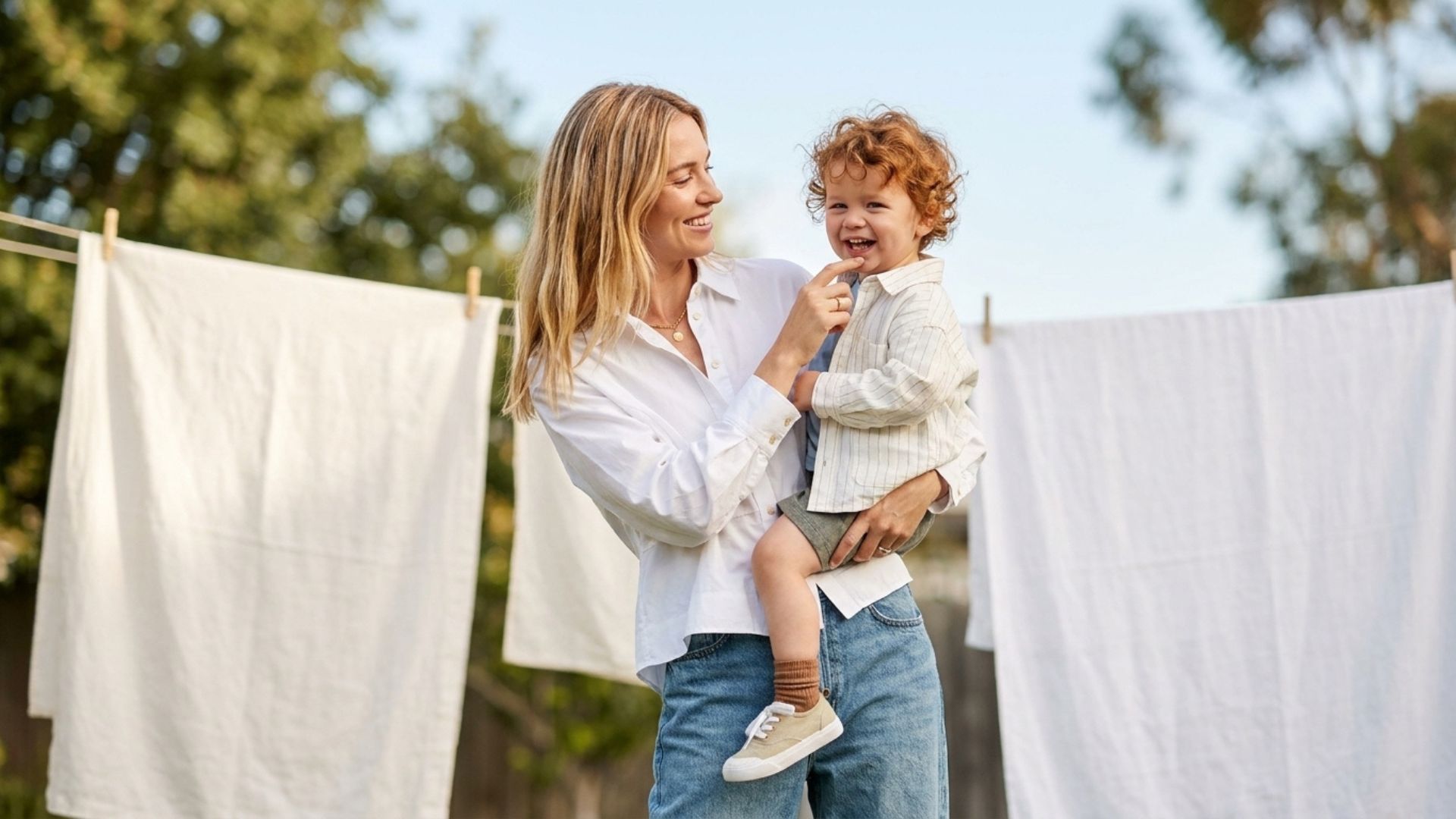 mother and son posing with a backdrop of fresh laundry