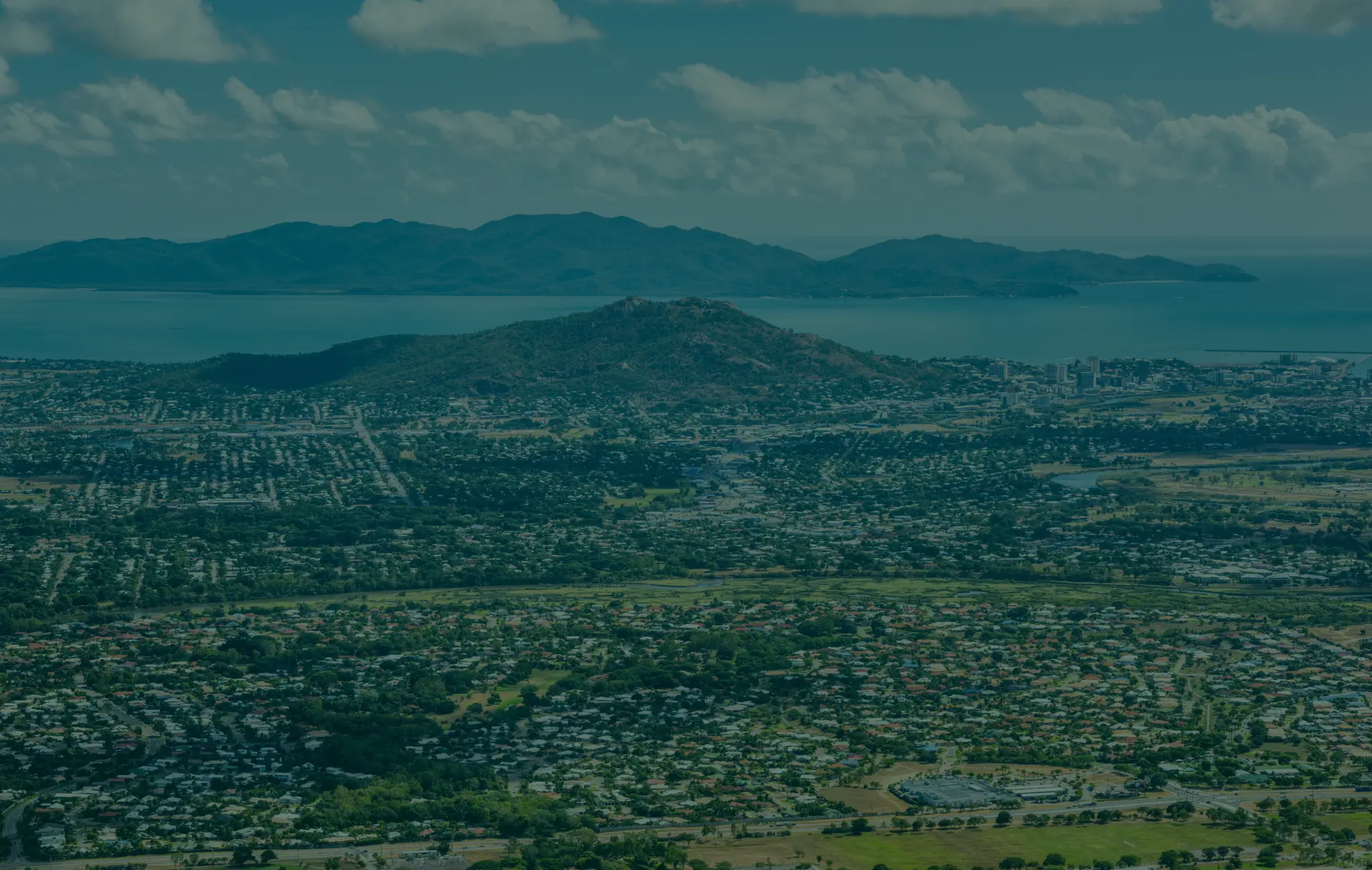 Coastal city nestled among hills, islands visible.