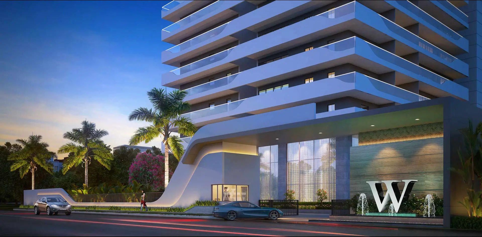 A man and woman sit on beige chairs in a modern room with a red paneled wall. A red pendant light hangs above a wooden coffee table between them.