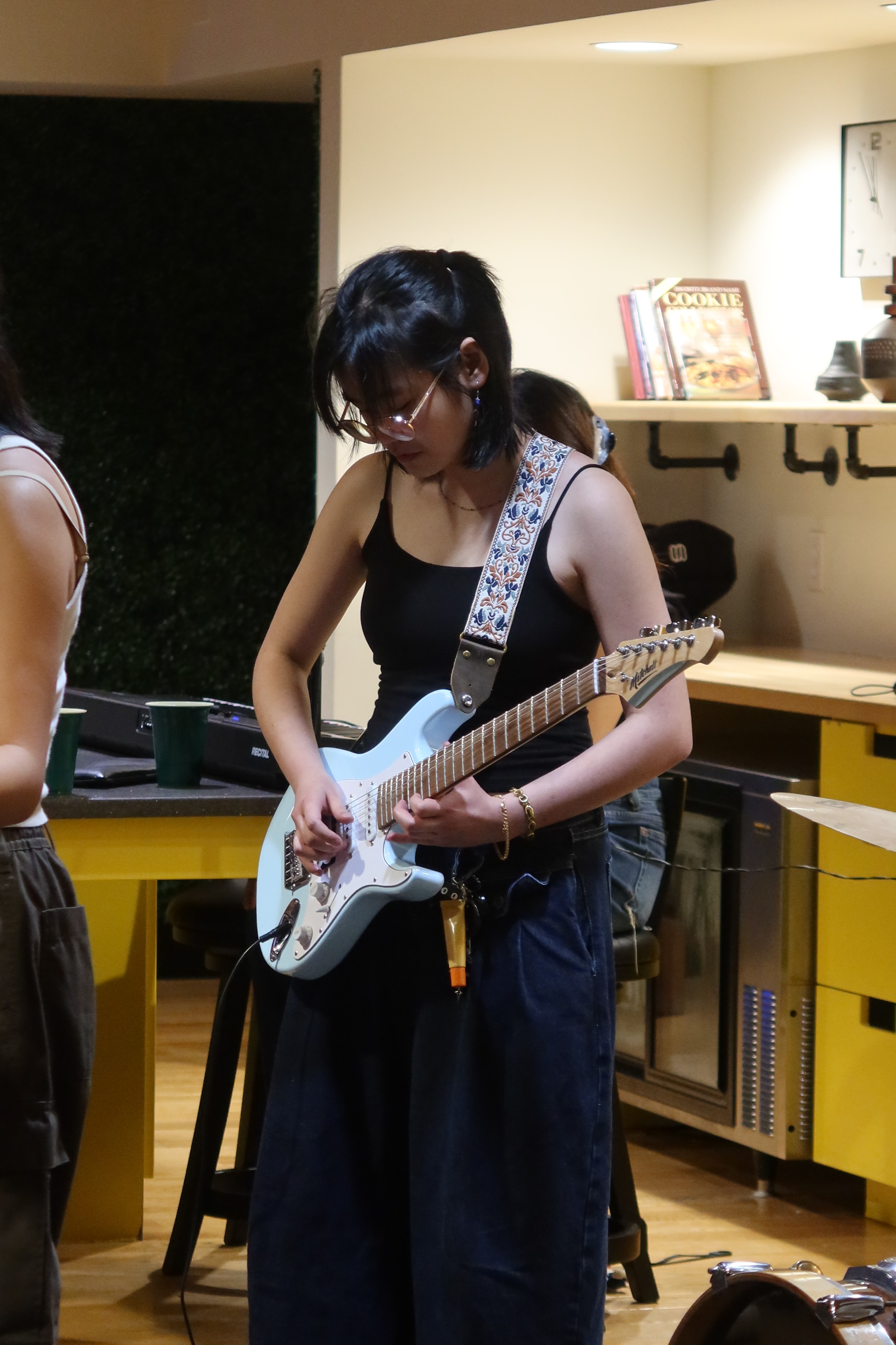 Full body photo of Natasha playing an electric guitar with her band