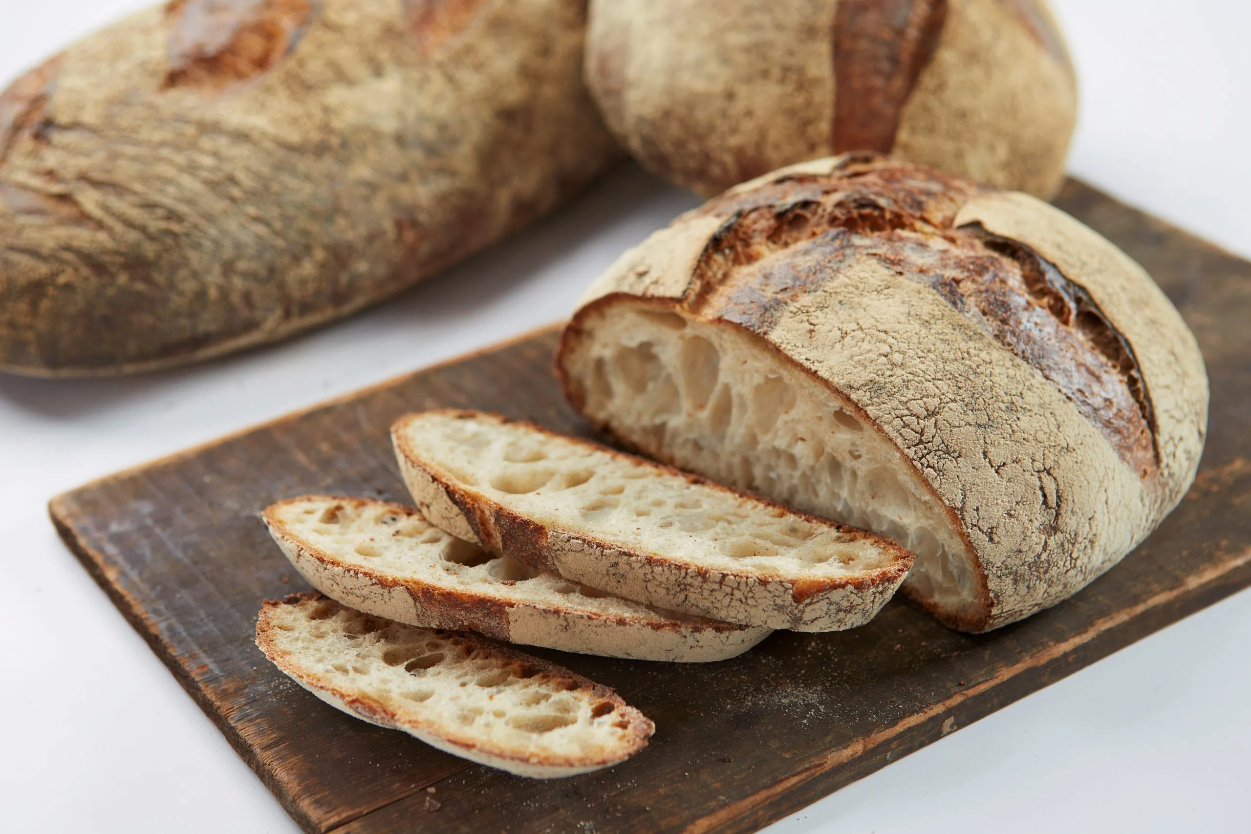 Sliced artisan bread loaves at Pain d'Avignon — open crumb sourdough and country bread on a wooden surface