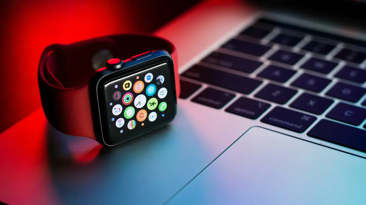 Apple Watch with red strap on a MacBook laptop