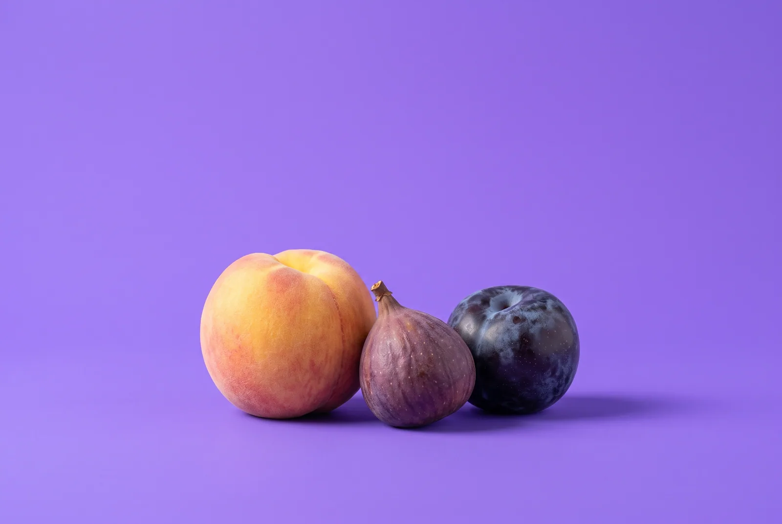 A peach, a fig and a plum leaning gently against each other in a small circle on a lilac backdrop, illustrating support for wives of porn addicts