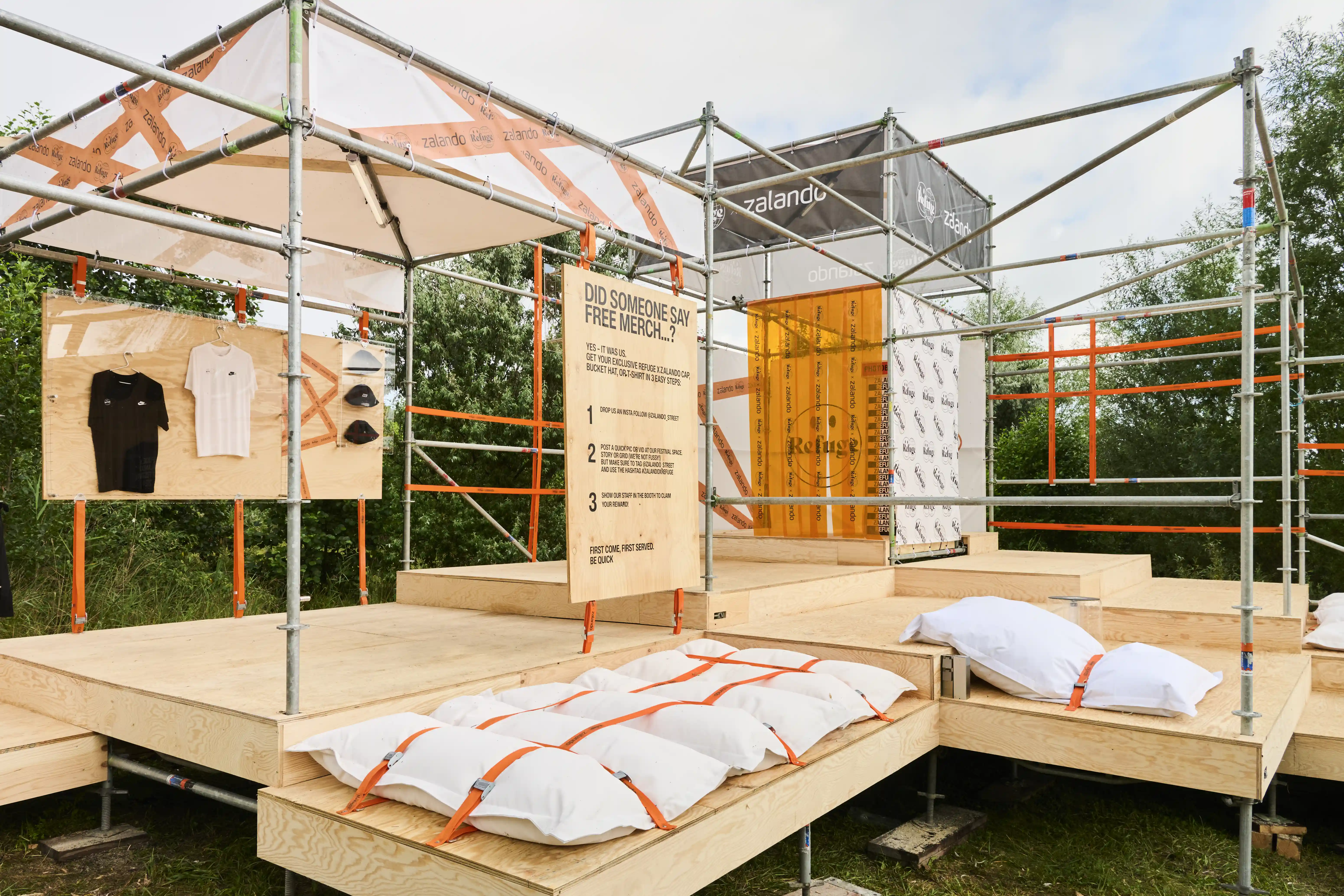 Wooden festival platform with merch board, pillow seating and Zalando scaffold cube.