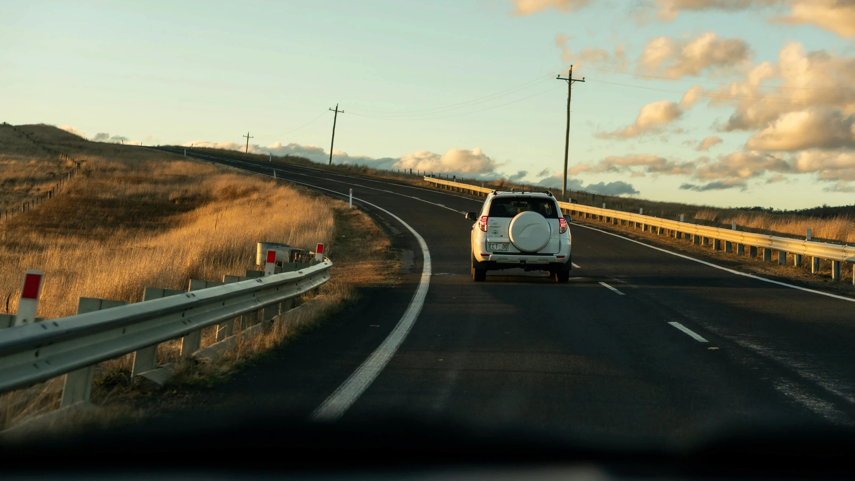 A white car driving on an empty road