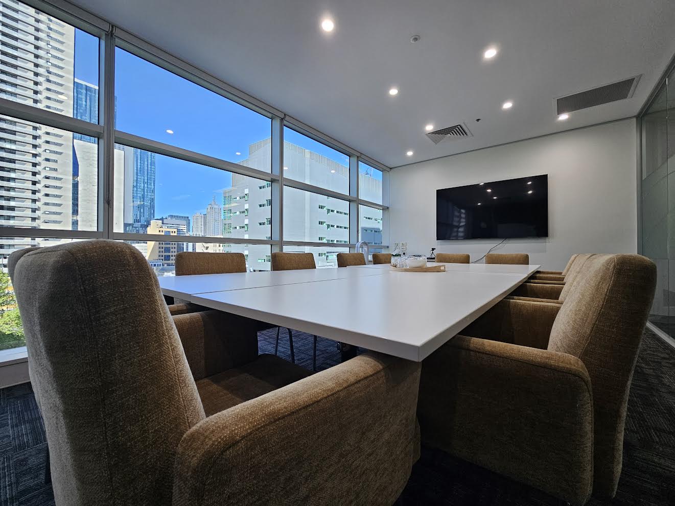 A confidential, secure room for mediation services, featuring six chairs, a table and a large window with a cityscape view.