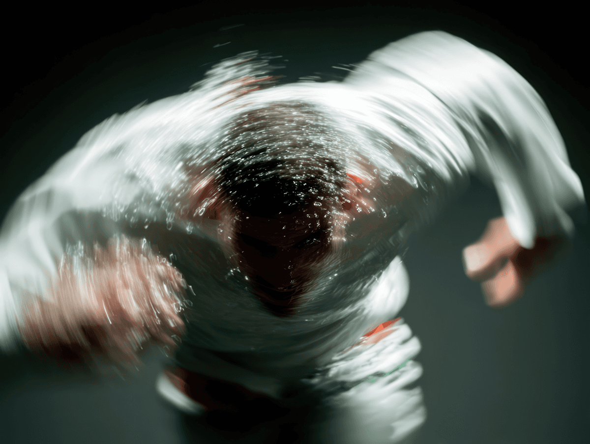 A dynamic shot of a person in motion with water droplets scattering, wearing a white outfit against a dark background.