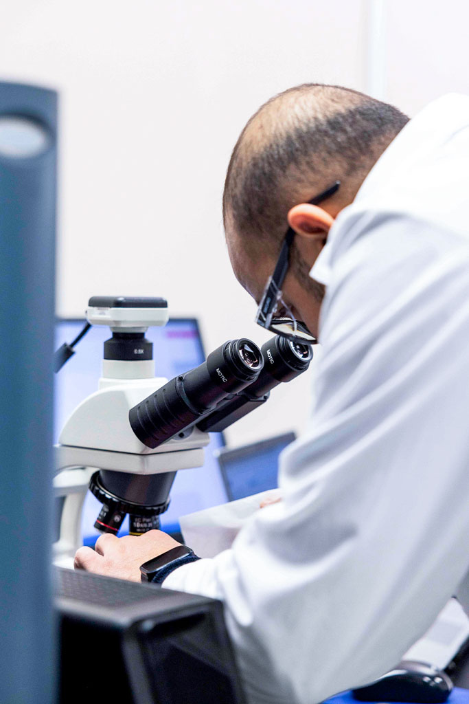 A SteriMax researcher in a white lab coat using a high-powered microscope in a laboratory.